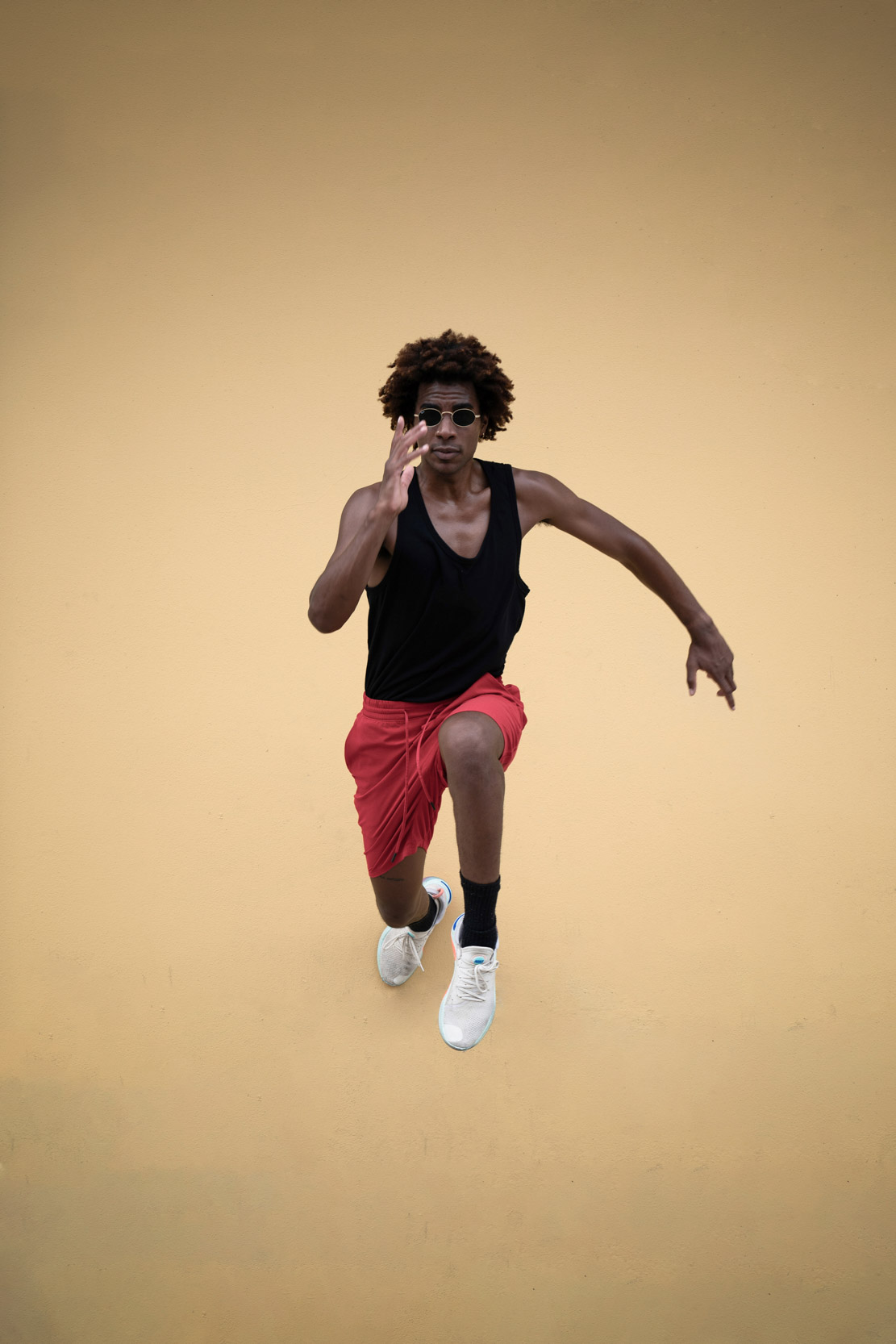 Model jumping in the air wearing fashionable outfit and glasses in New Orleans