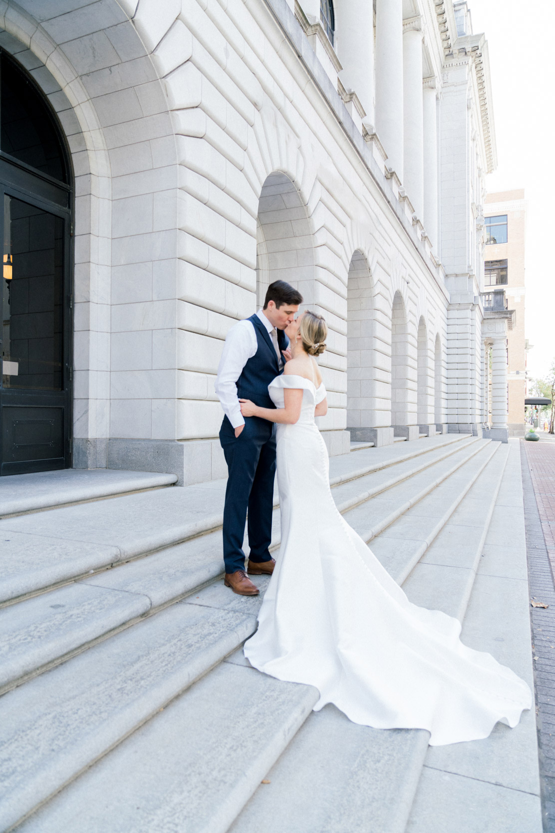 bride and groom on steps kissing at Lafayette Square in New Orleans