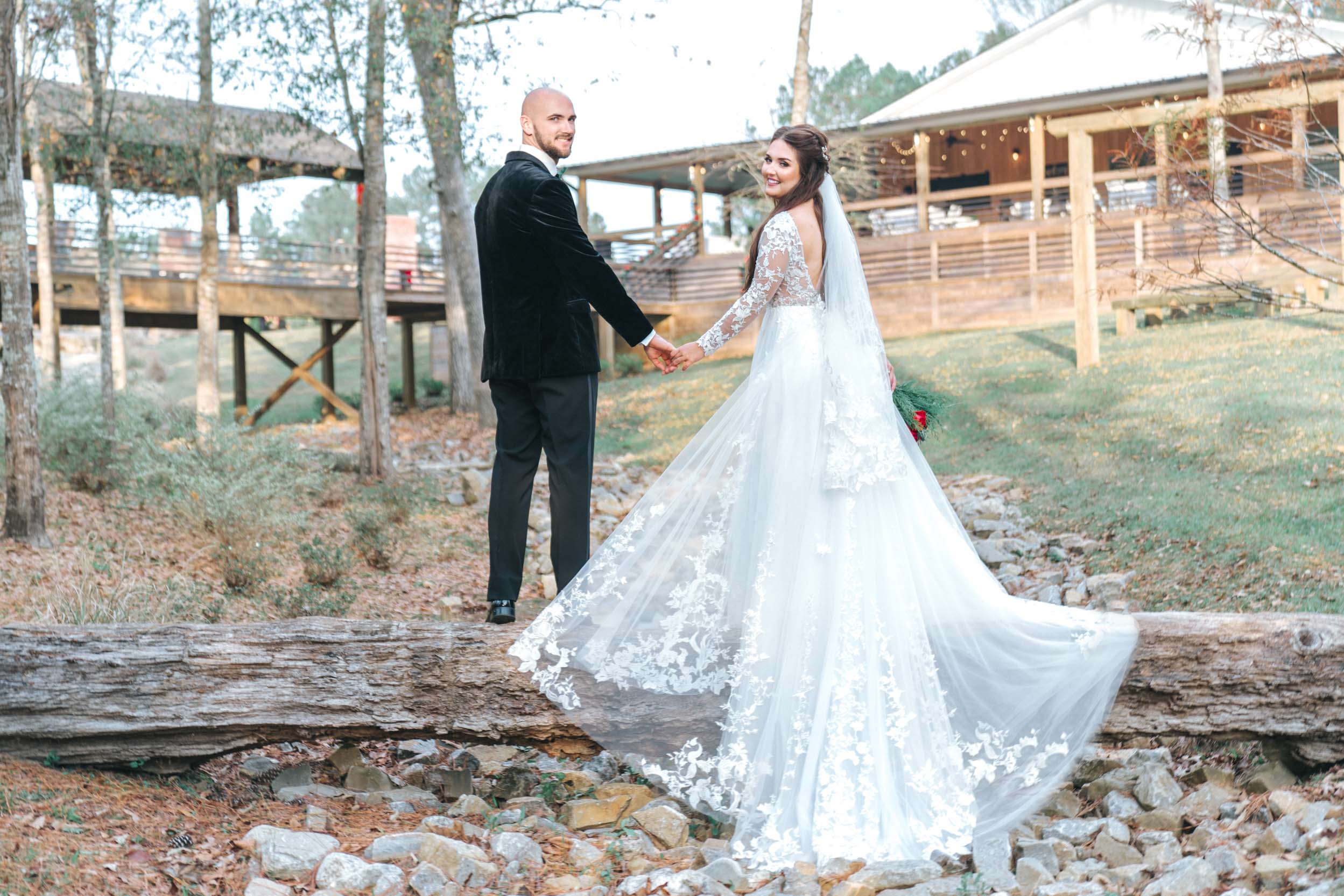 Bride and groom standing on log and creek at Creekview Barn in Mississippi