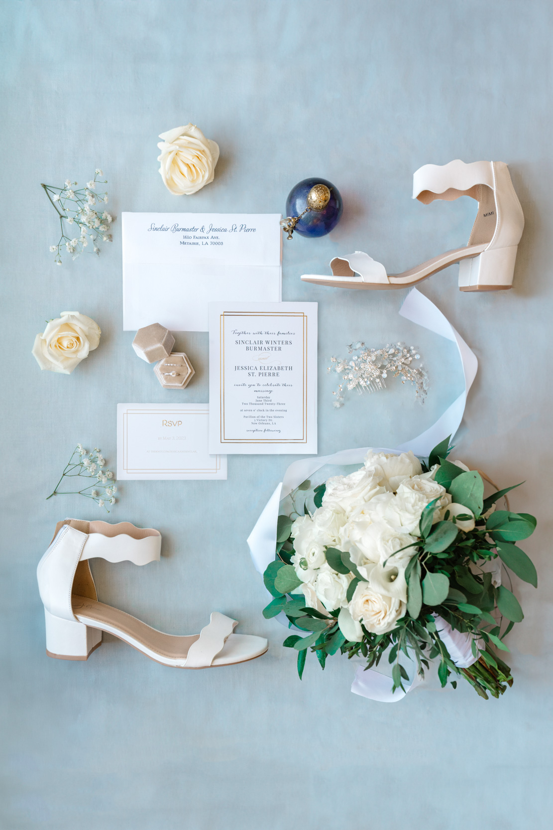 wedding flat lay of bridal shoes, flowers, invitation, and rings