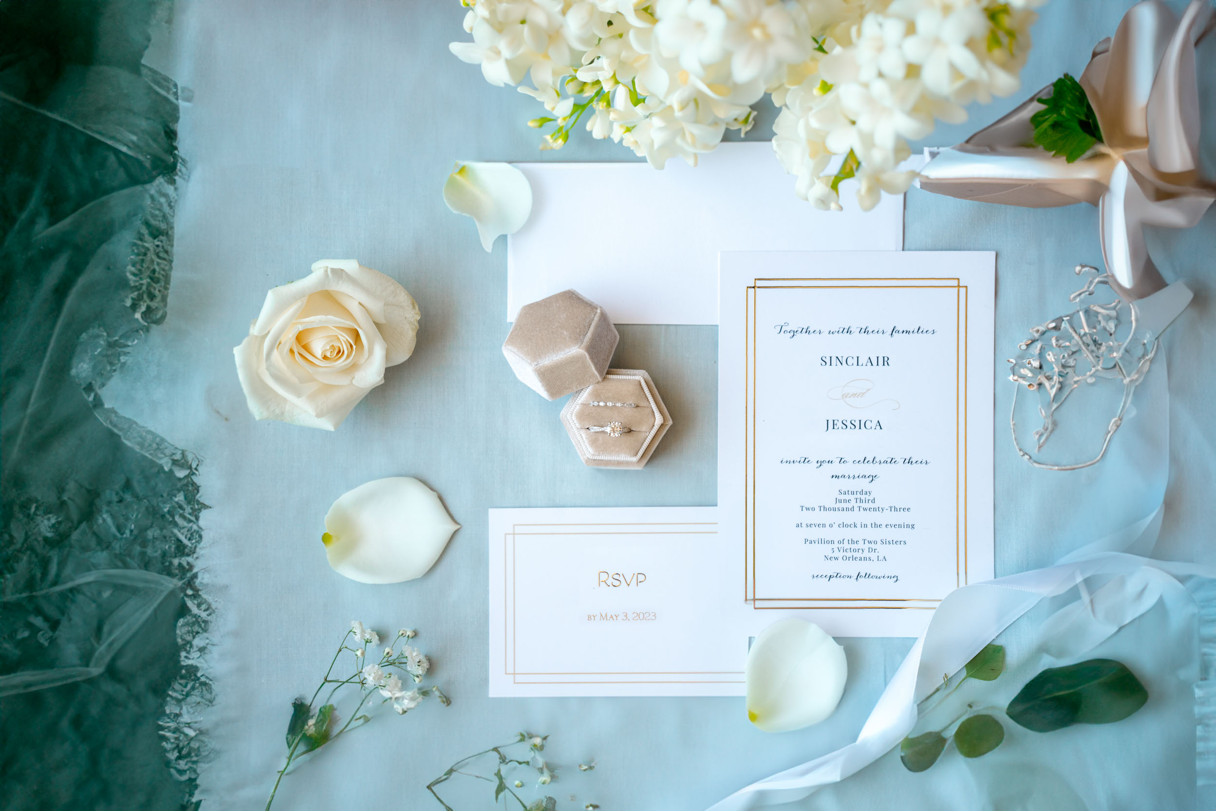 wedding flat lay of rings, invitations, rose pedals