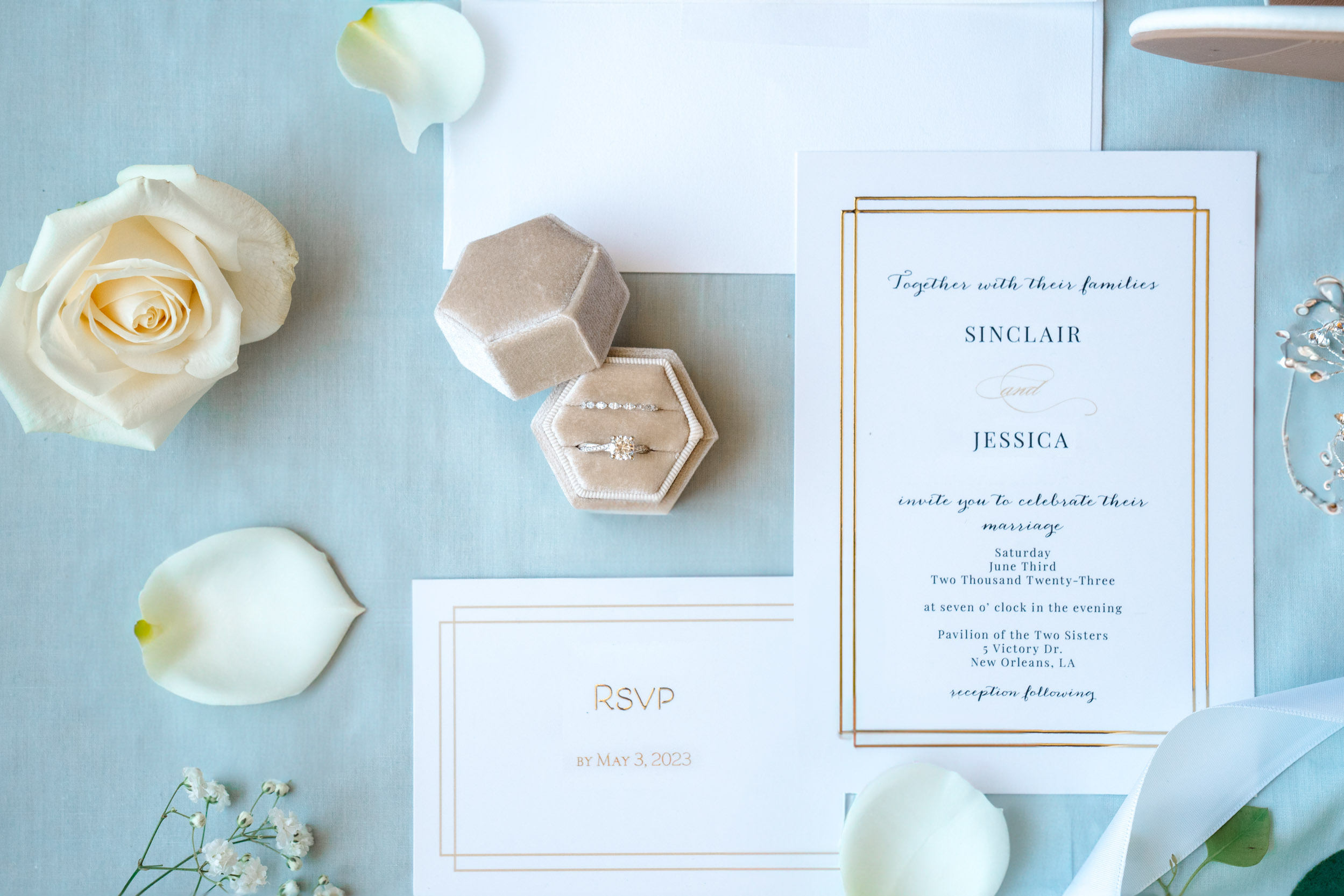 wedding flat lay of rings, invitations, rose pedals