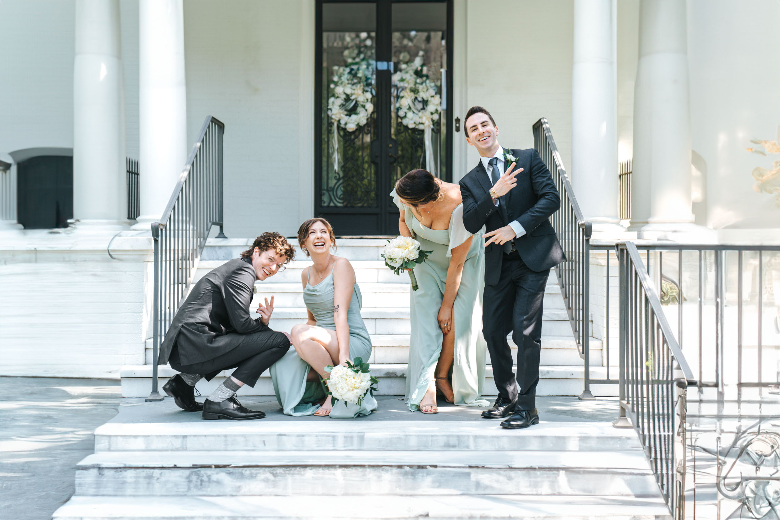 Wedding party laughing on steps in front of uptown mansion in New Orleans