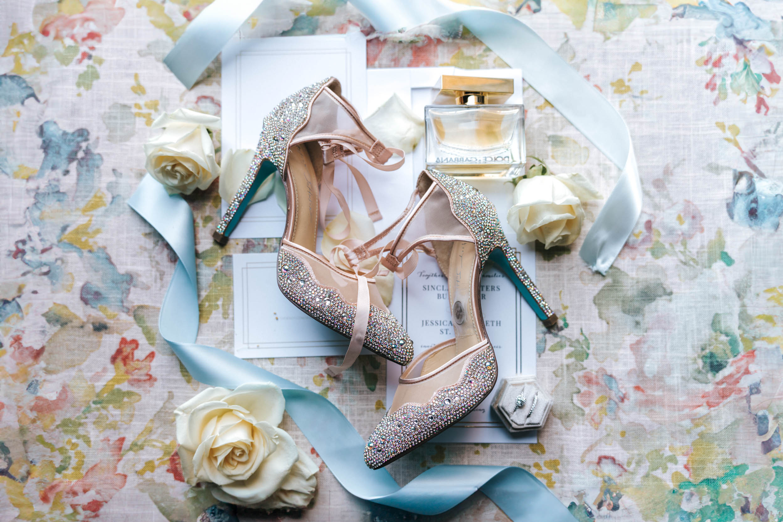 wedding flat lay with shoes, perfume,invitations, and rings