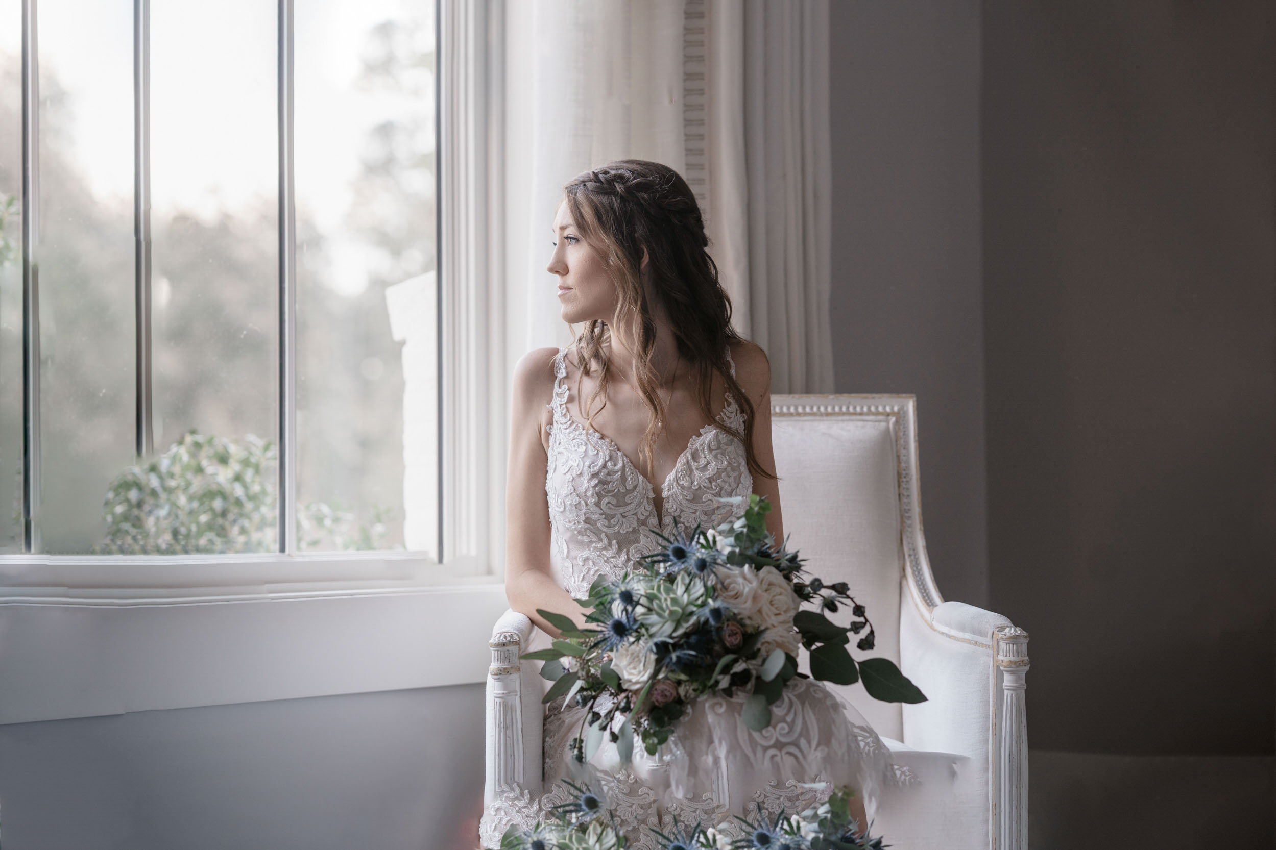 bride looking out window with flowers on her wedding day