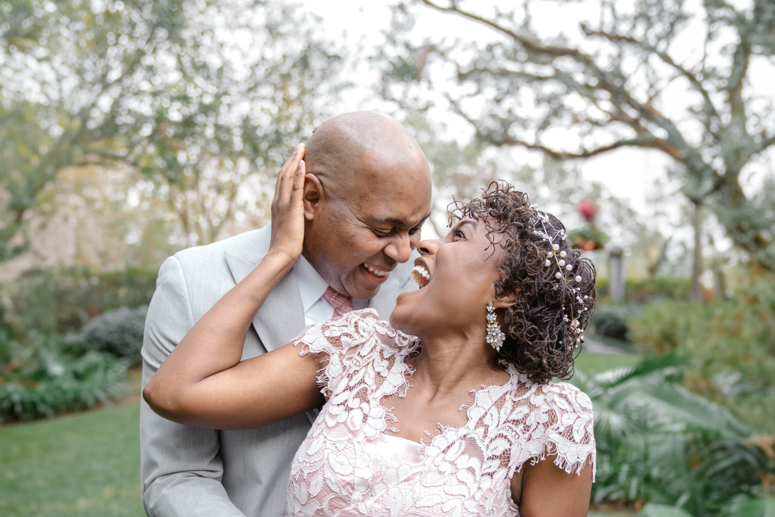 bride and groom hugging and laughing on wedding day at Audubon Park in New Orleans