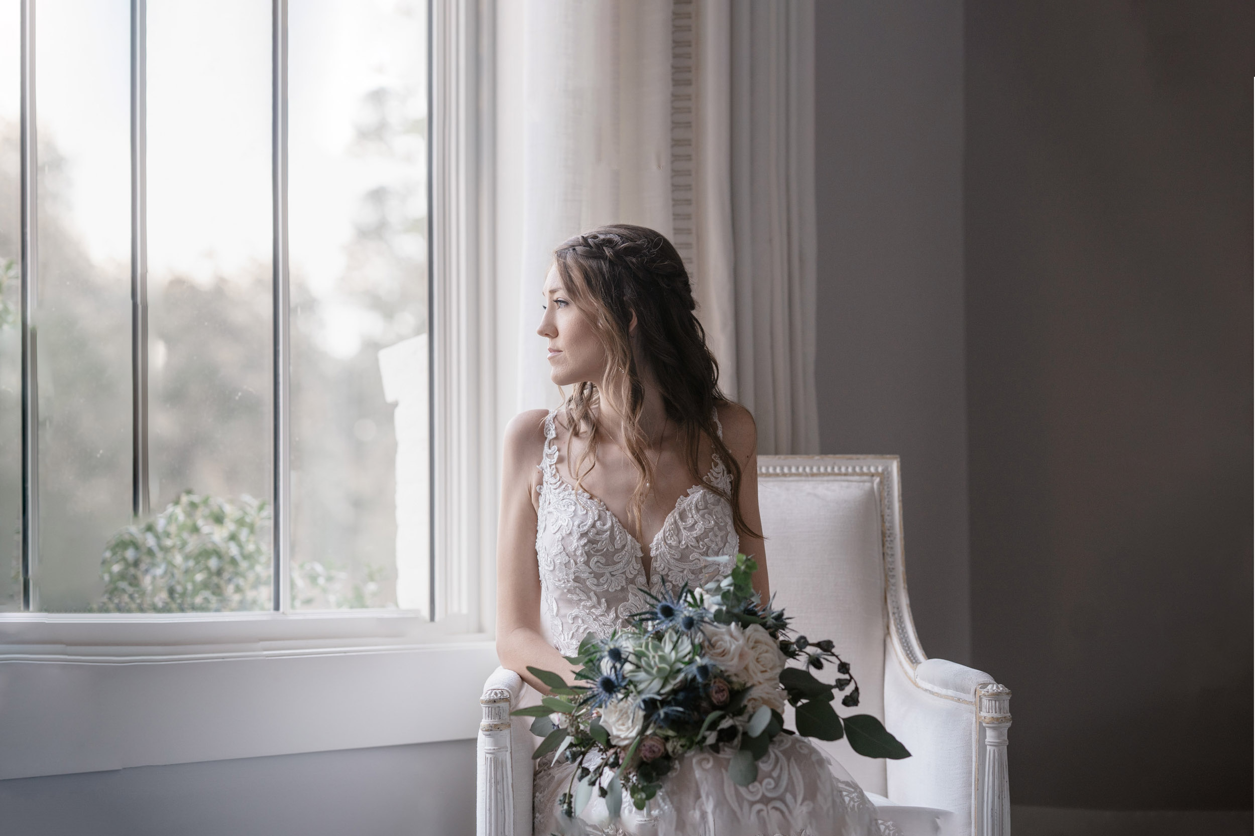 bride looking out window with flowers on her wedding day