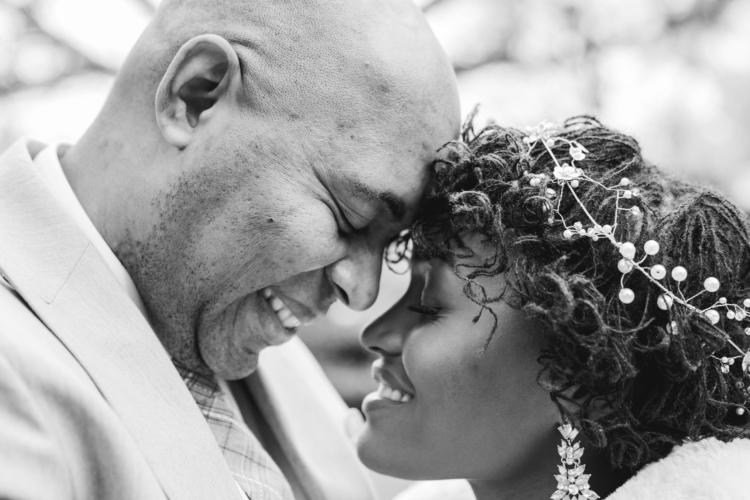 African American bride and groom touching foreheads and smiling on wedding day