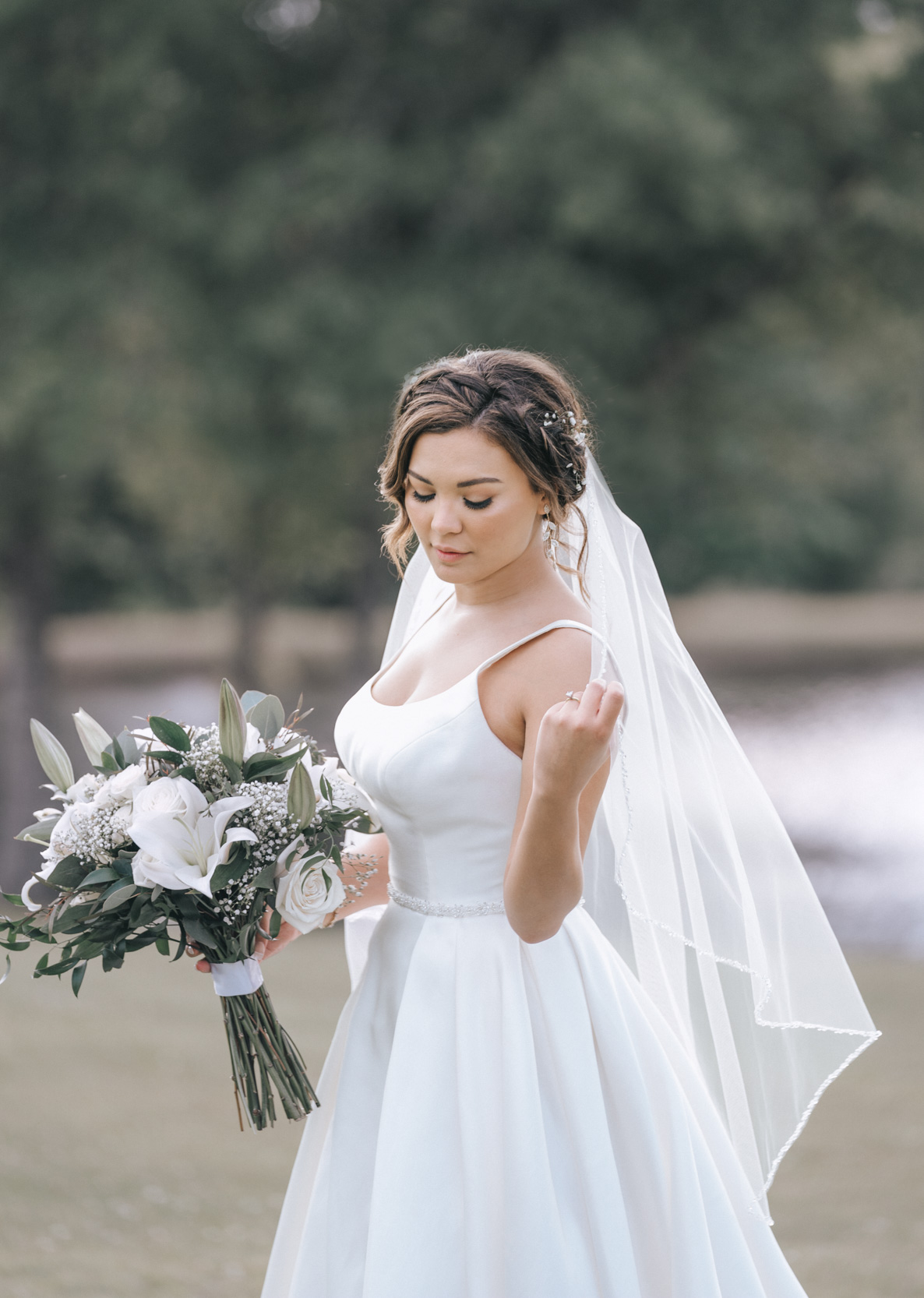 bride with flowers and veil in a field at White Magnolia in Louisiana