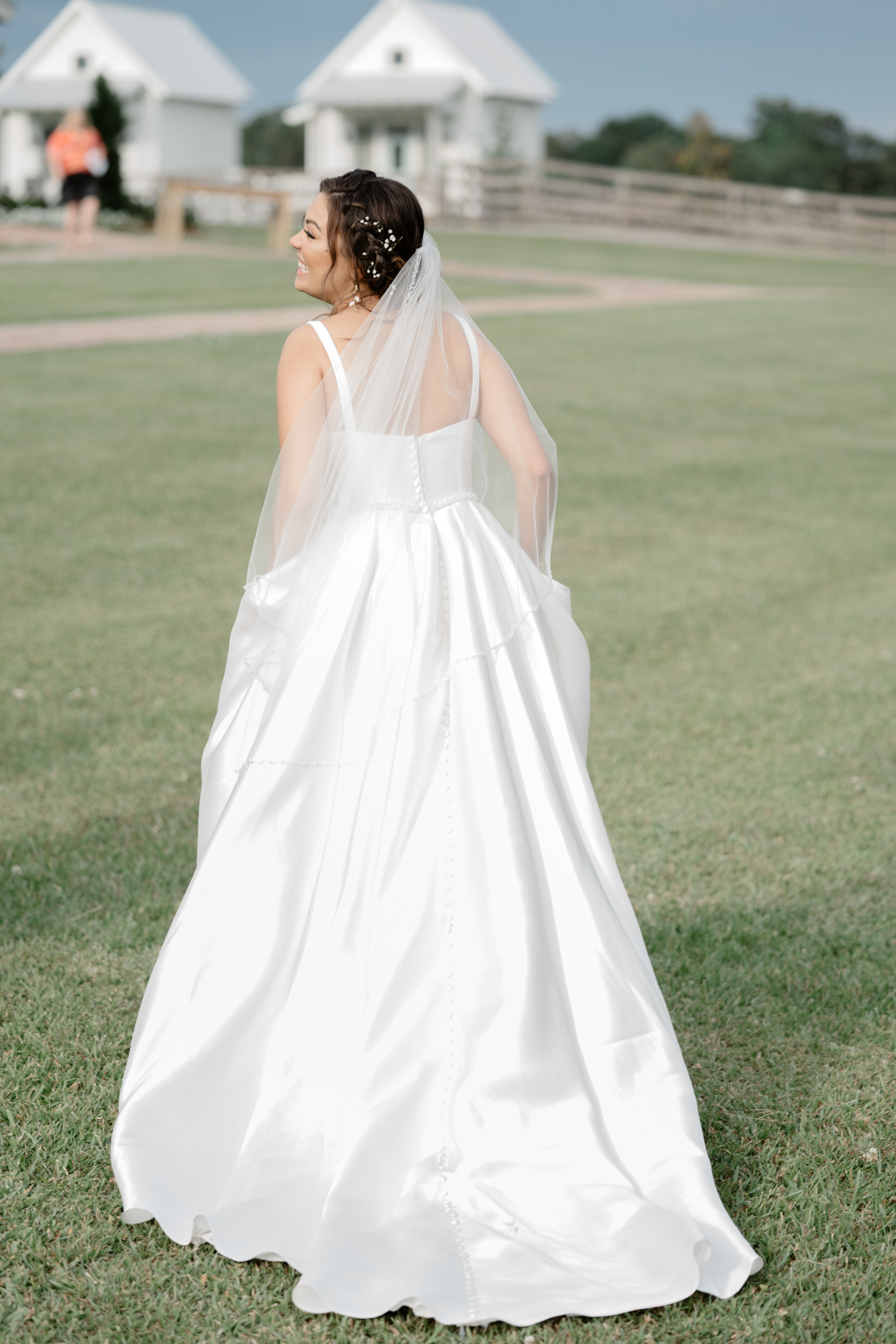 bride holding her dress out and laughing in front of White Magnolia