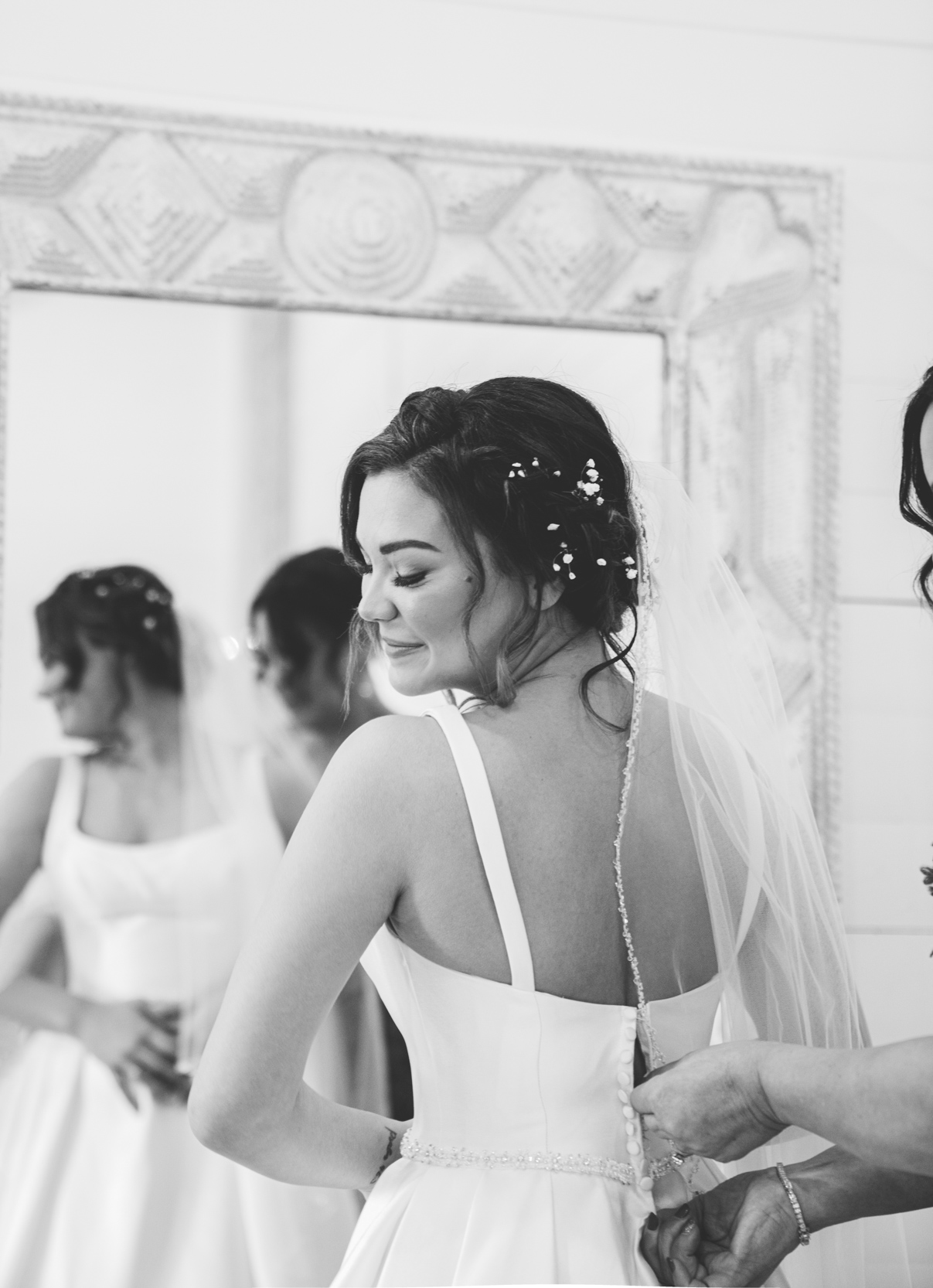 bride getting buttoned up in mirror by her mother at White Magnolia in Kentwood, Louisiana