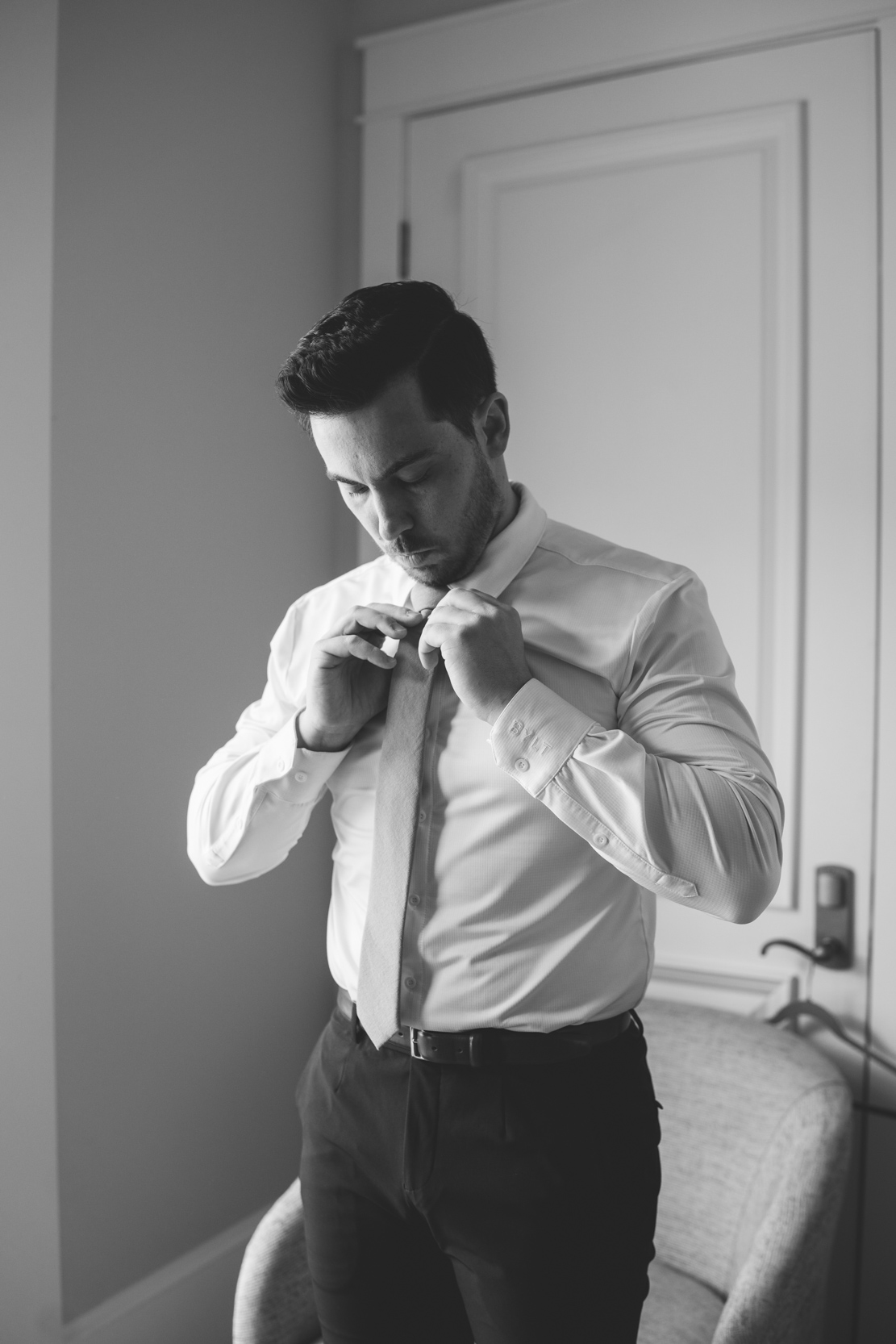 groom putting on his tie at a church in Covington, Louisiana