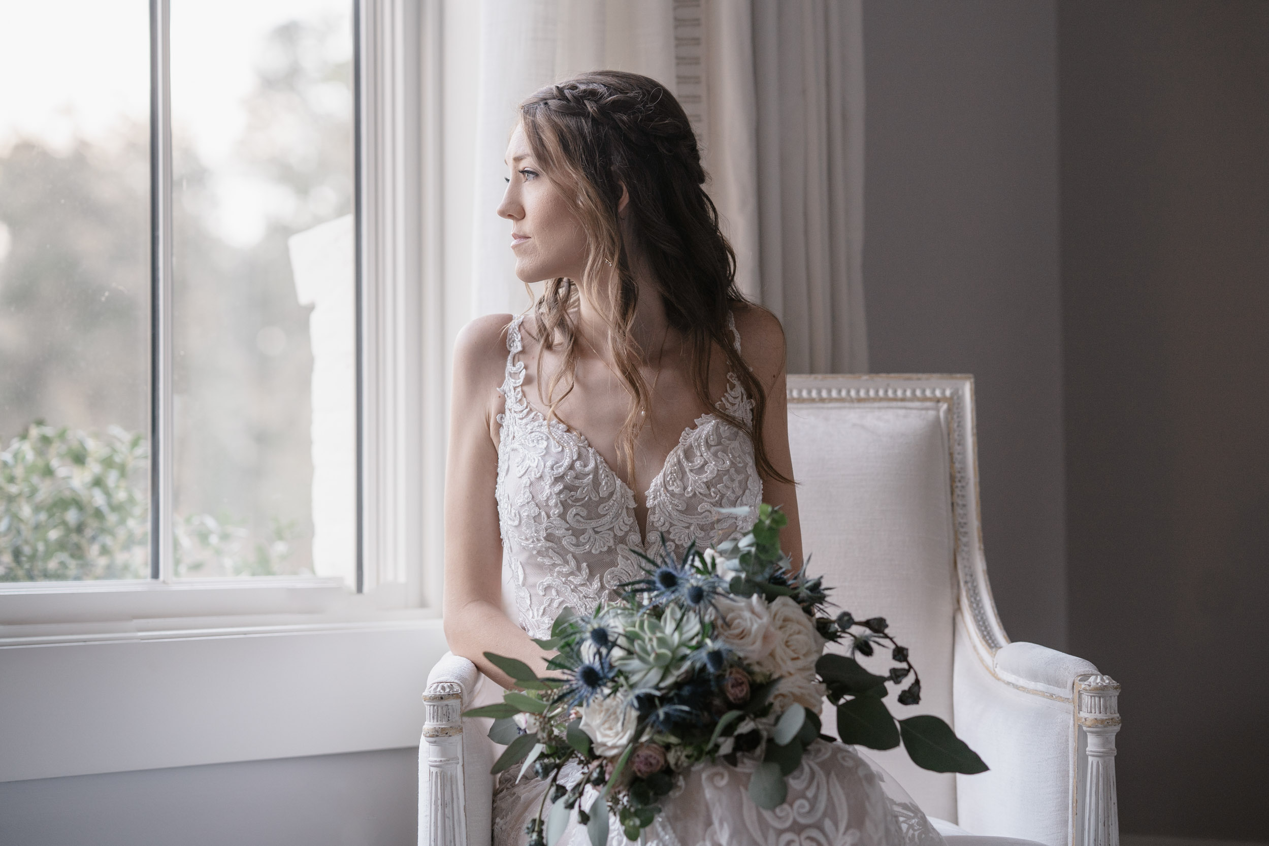 bride looking out window with flowers on her wedding day at First Baptist Church in Covington, Louisiana