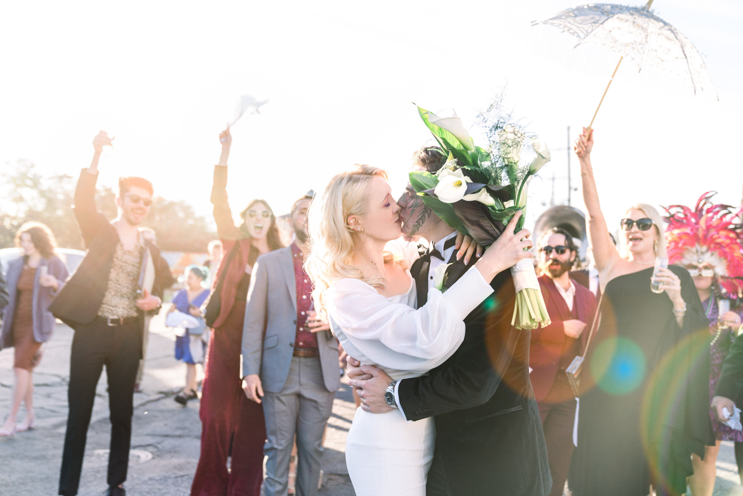 Bride and groom kissing during wedding parade in New Orleans Bywater