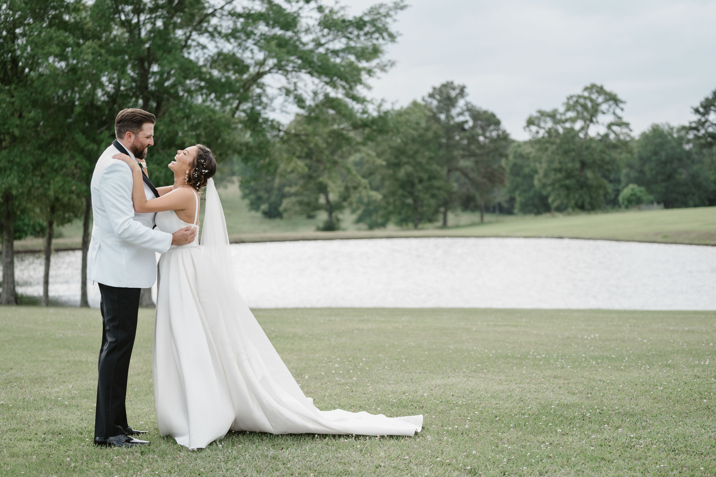 bride and groom laughing in a field at White Magnolia in Kentwood, Louisiana