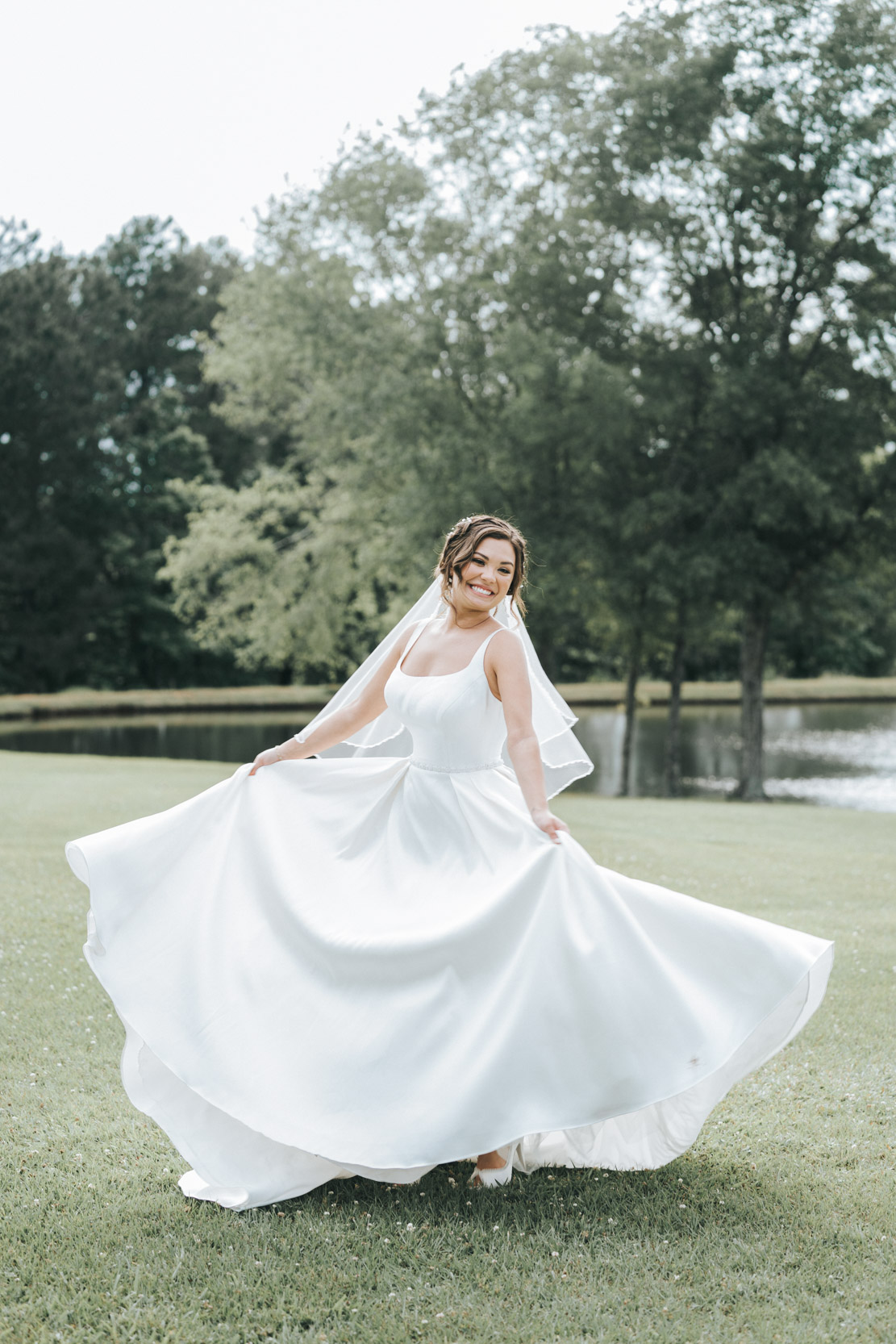 bride playing with dress in a field at White Magnolia in Louisiana