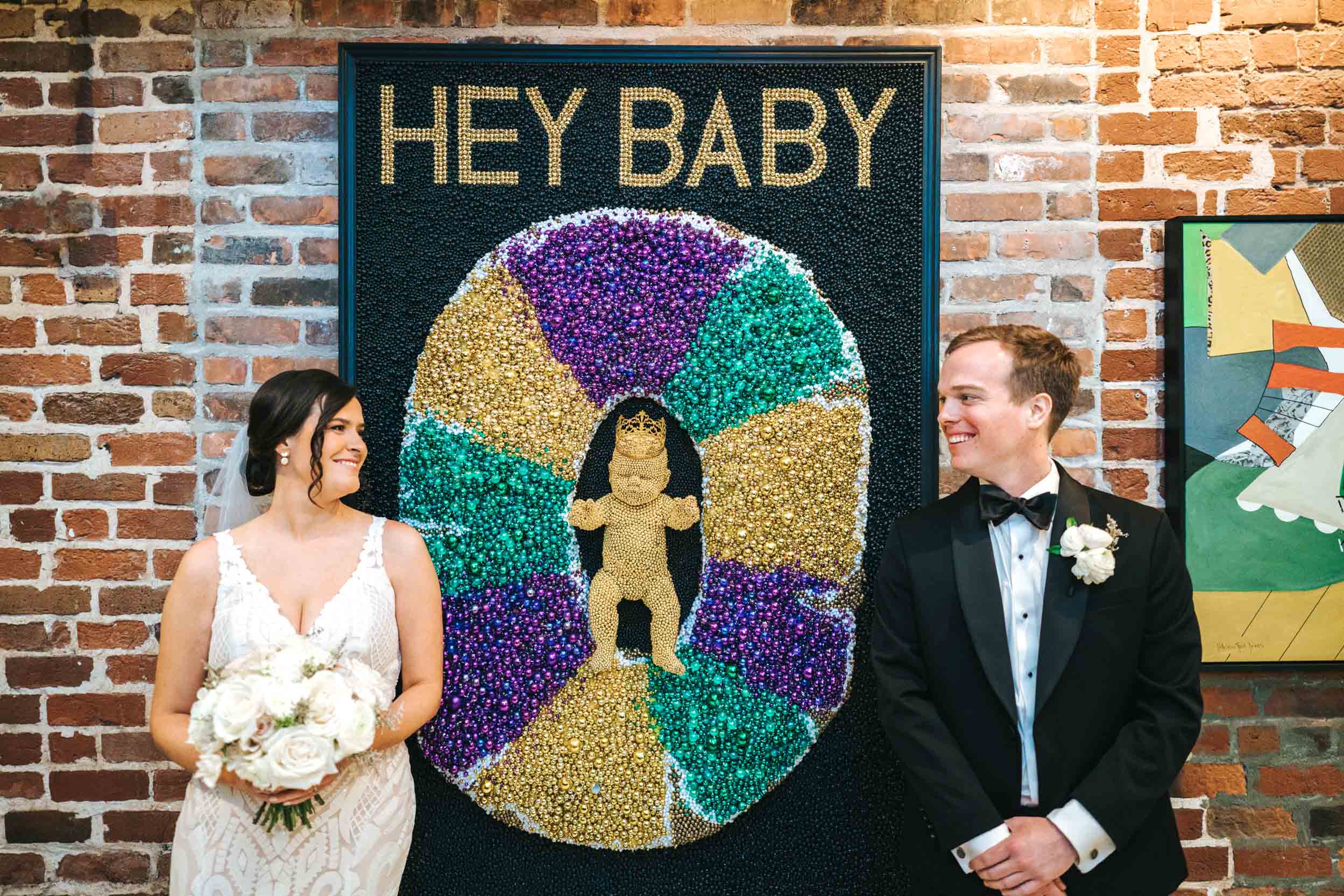 Bride and groom smiling in front of Mardi Gras bead mural at the Old 77 Hotel in New Orleans