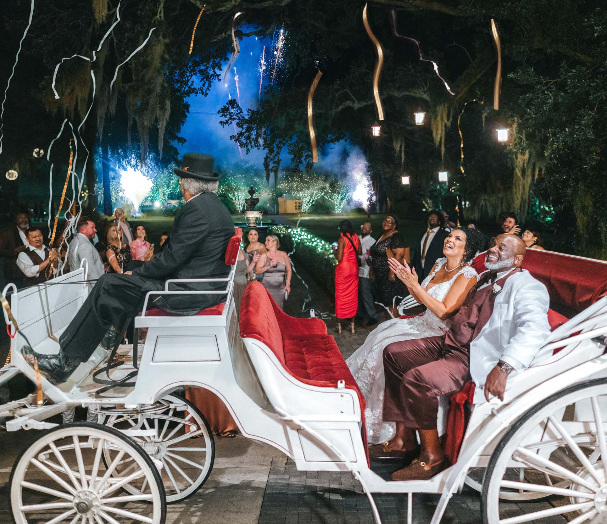 African American bride and groom celebrating under fireworks and streamers on horse carriage ride at The Southern Oaks in New Orleans