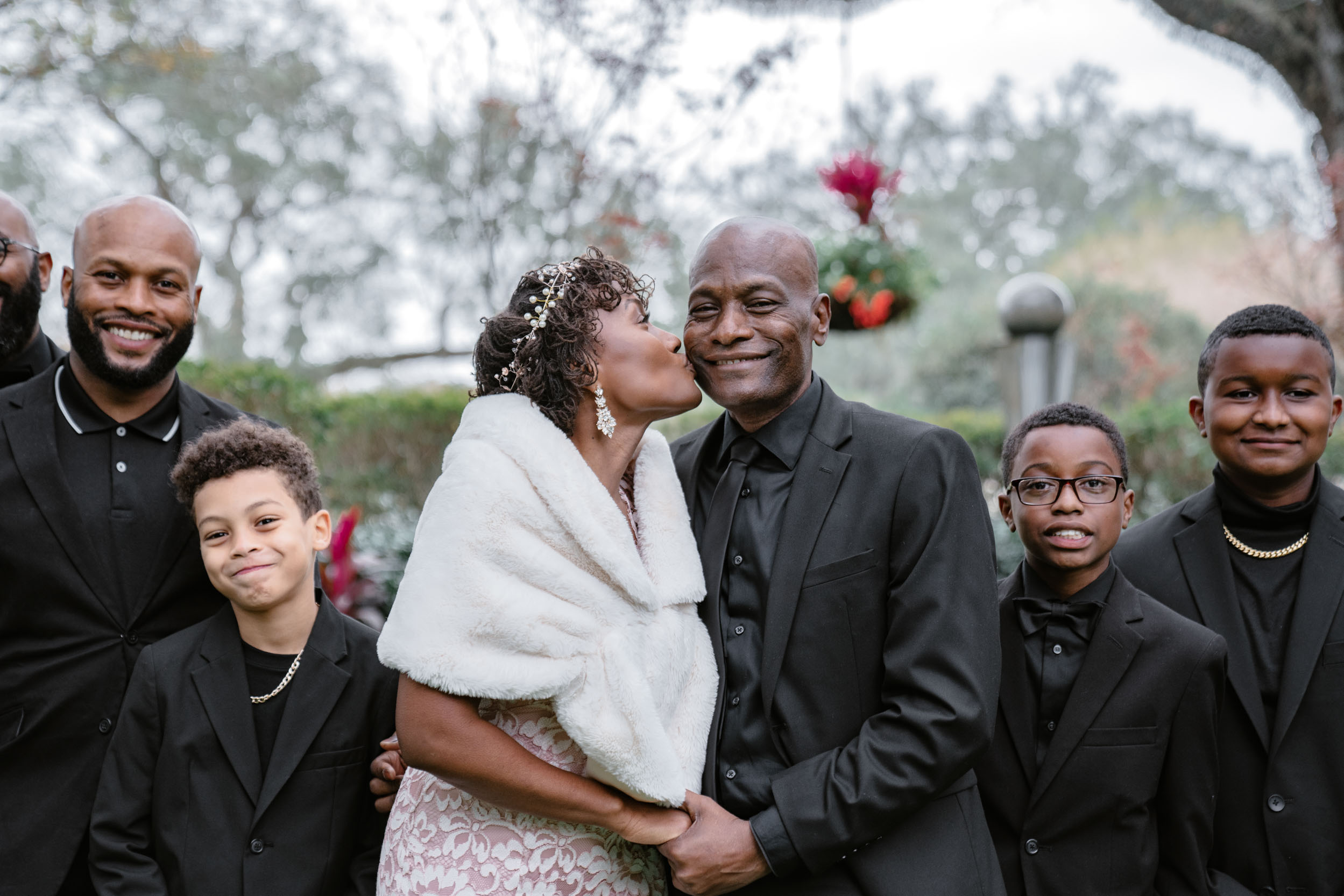 African American bride kissing her father in garden on wedding day at Audubon Park in New Orleans