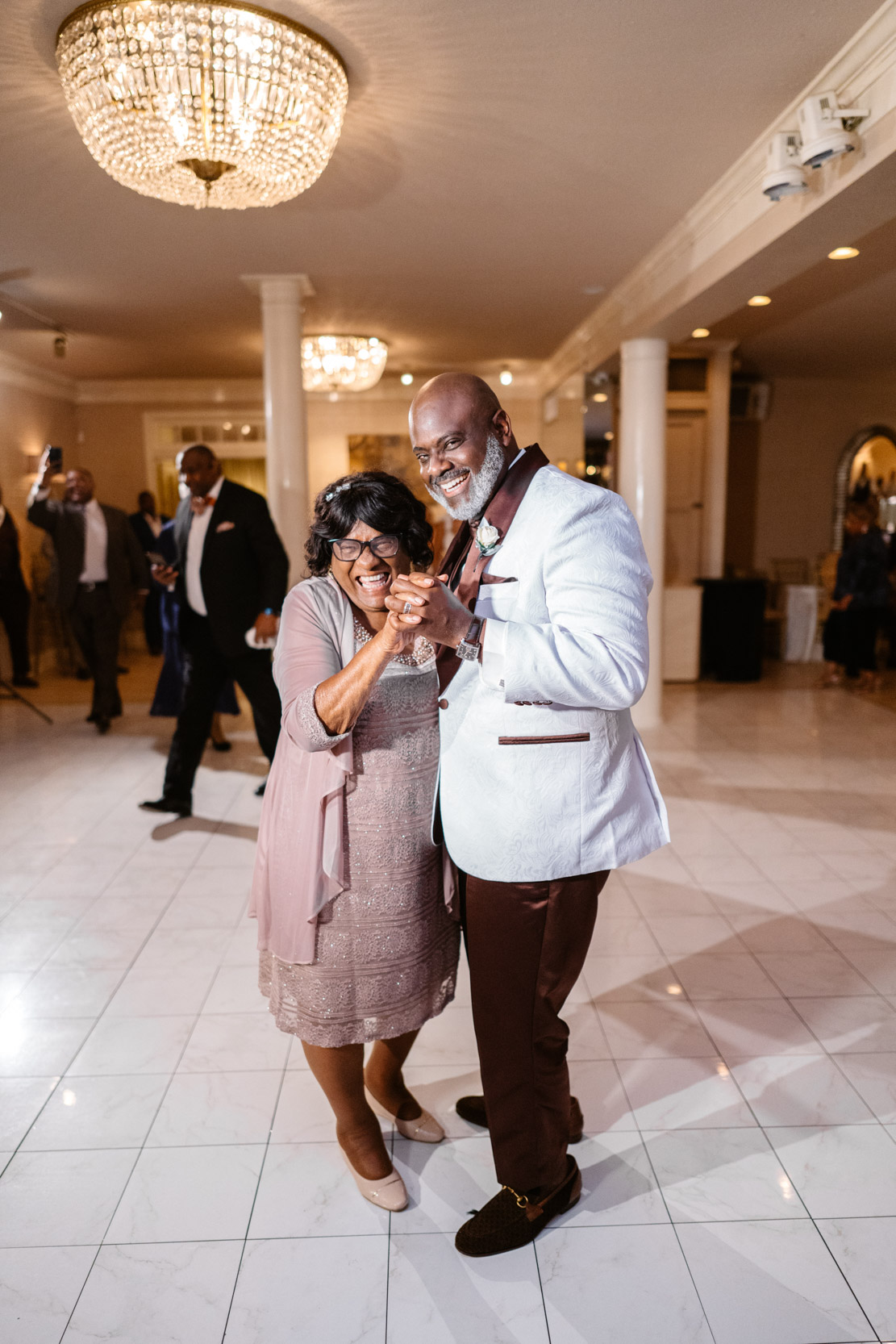 African American groom and his mother dancing and laughing on wedding day at the Southern Oaks in New Orleans