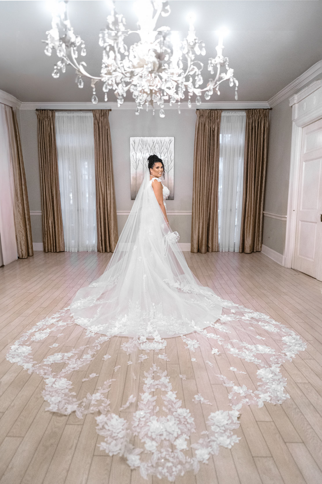 Beautiful African American bride posing under chandelier with wedding dress train at The Southern Oaks in New Orleans