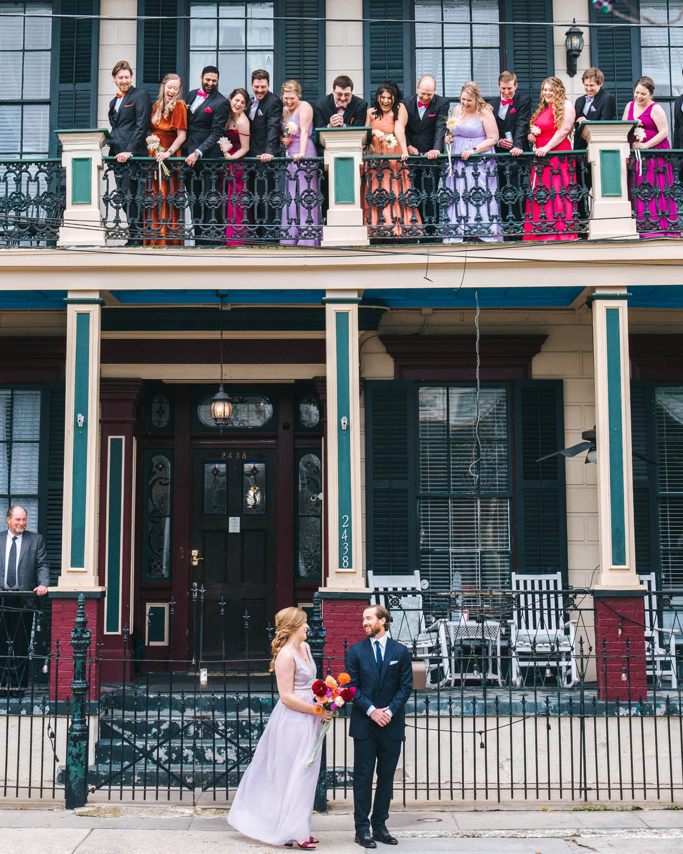 First look with bride and groom in front of mansion in the New Orleans Bywater with wedding party watching from balcony