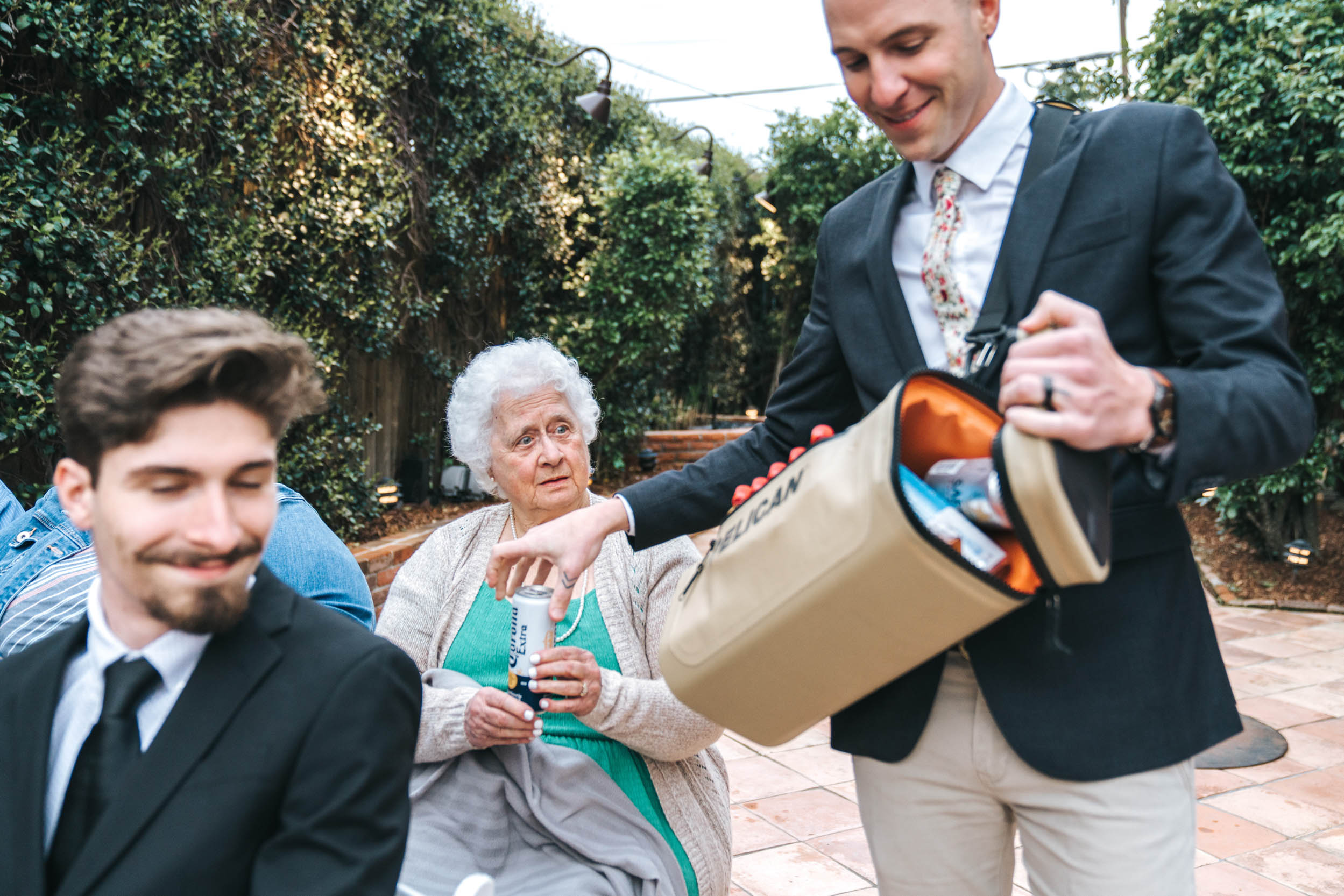 Groomsman handing out High Noon beverage to elderly grandmother during wedding ceremony at Rosy’s Jazz Hall in New Orleans