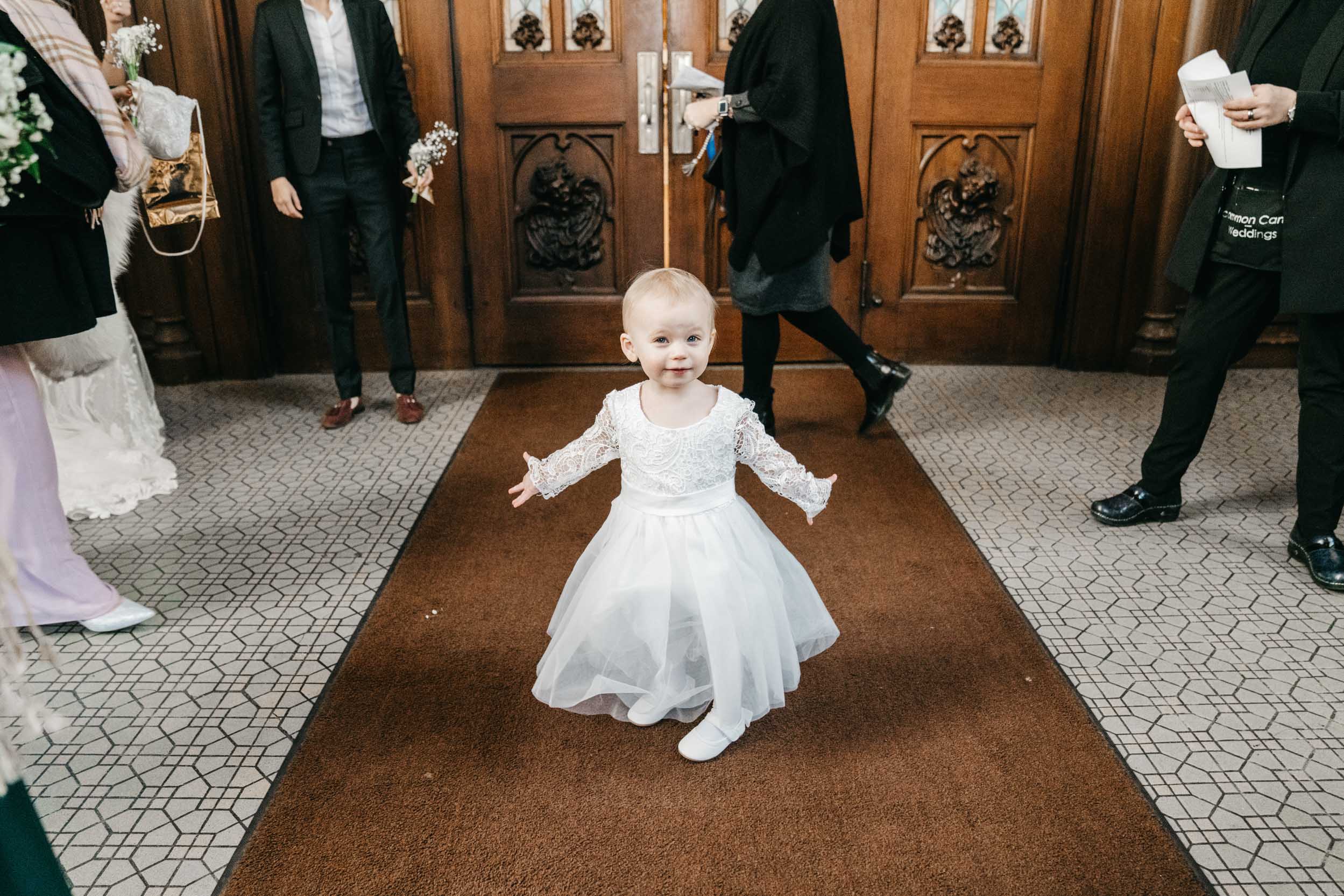 baby wearing white dress and dancing before wedding ceremony at St. Patrick’s Cathedral in New Orleans