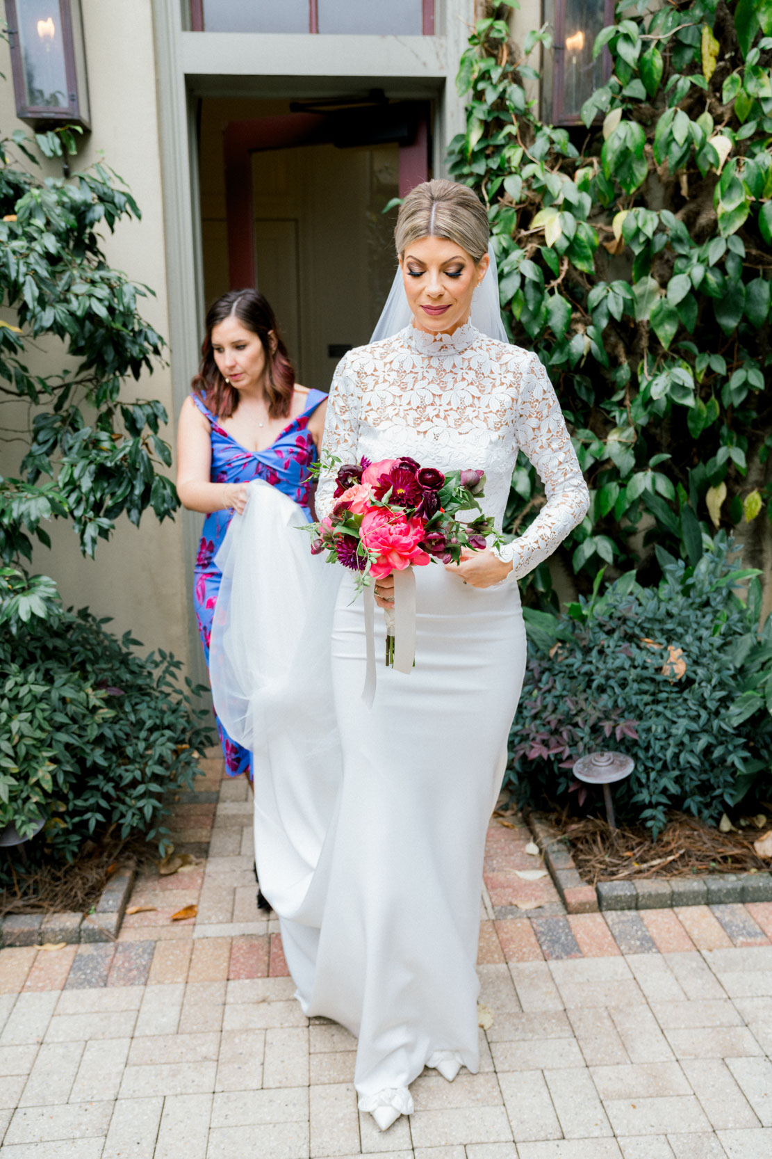 beautiful bride in Chantilly laced wedding dress with bridesmaids holding dress and Petals and Parties flowers at the Southern Hotel in Covington, Louisiana