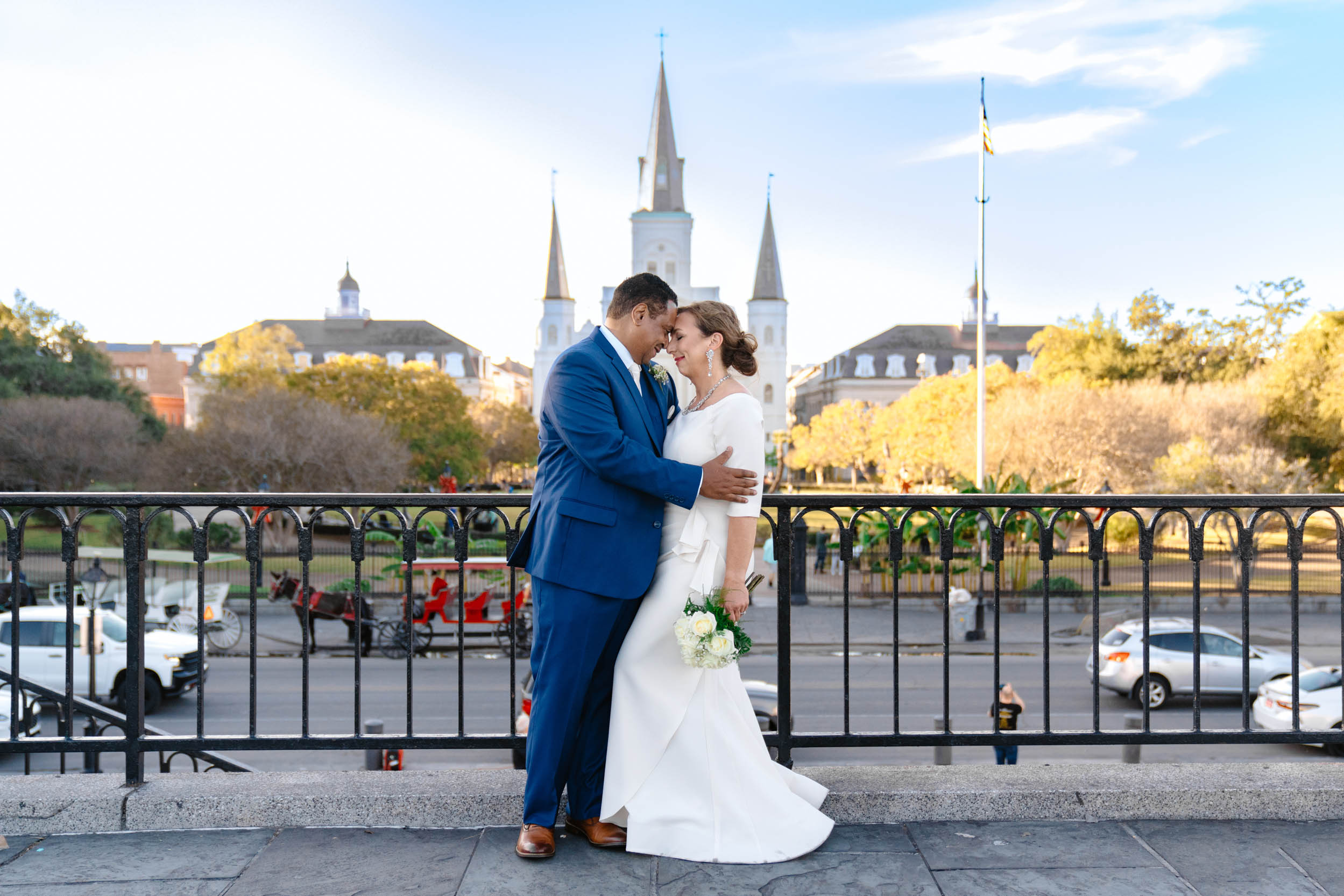 bride and groom holding each other in front of Jackson Square skyline in the French Quarter New Orleans