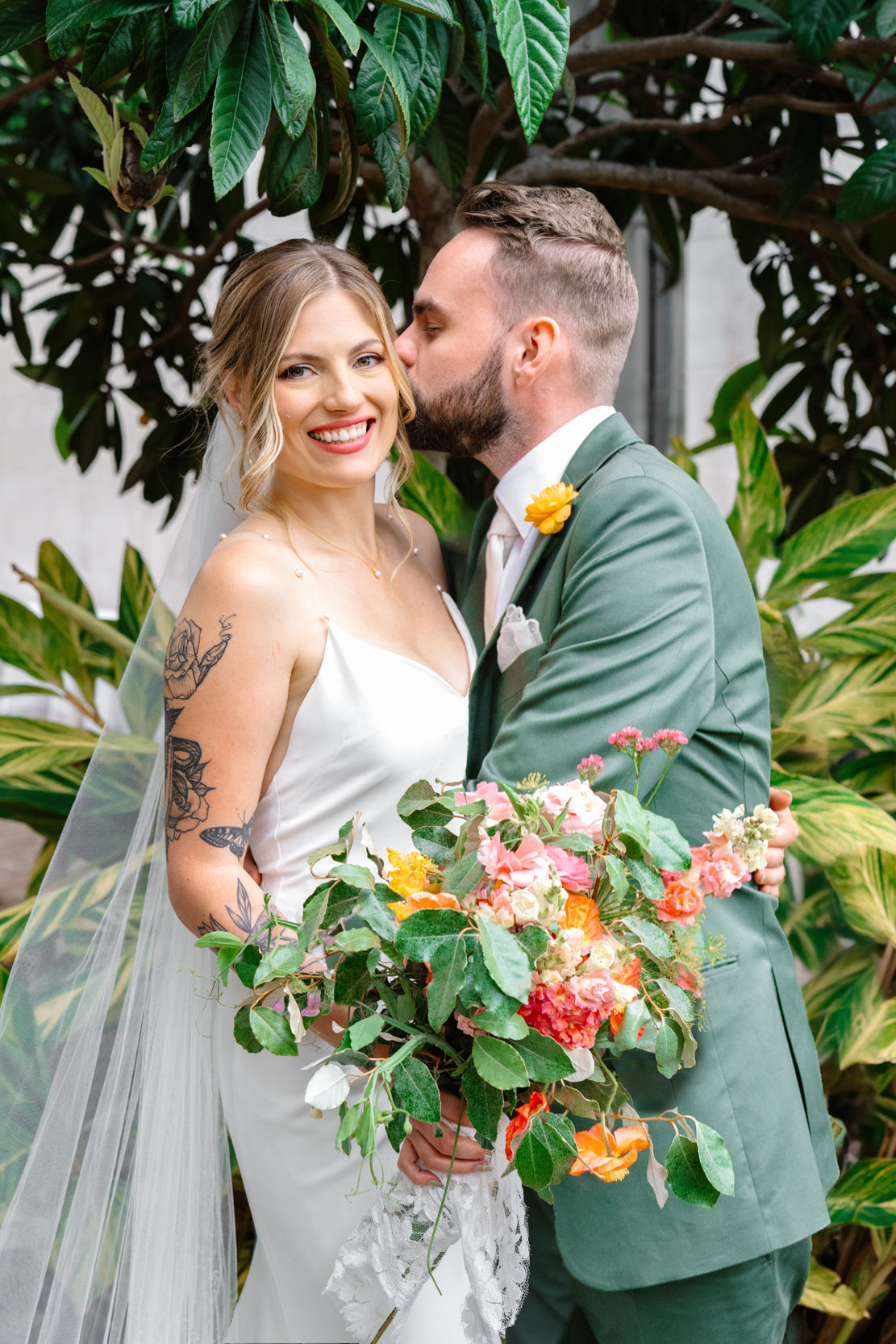 bride and groom hugging and kissing on wedding day with Cicada Calling flowers at Margaret Place in New Orleans