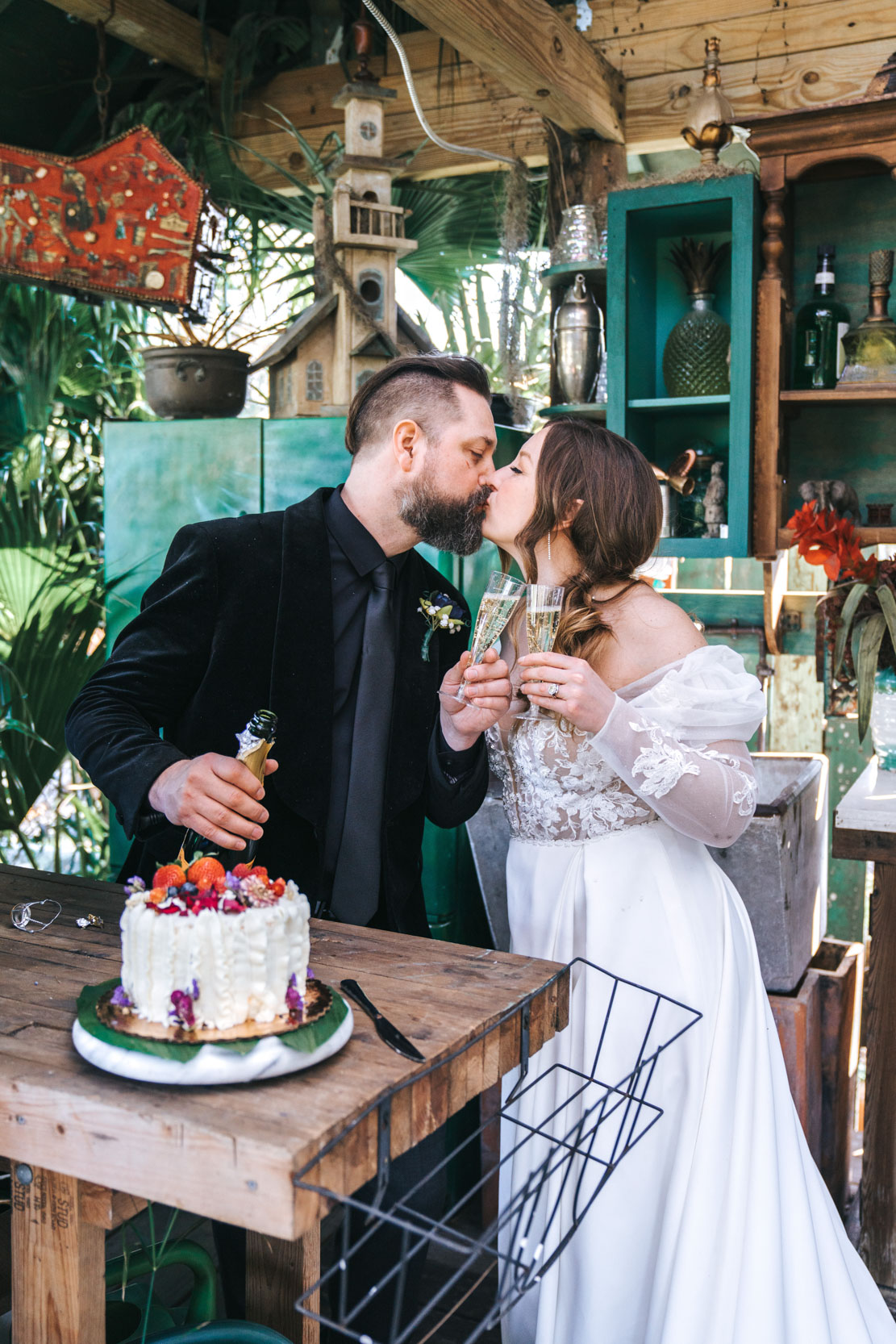 bride and groom kissing and toasting champagne with Chantilly strawberry cake at the Emerald Door in the New Orleans Bywater