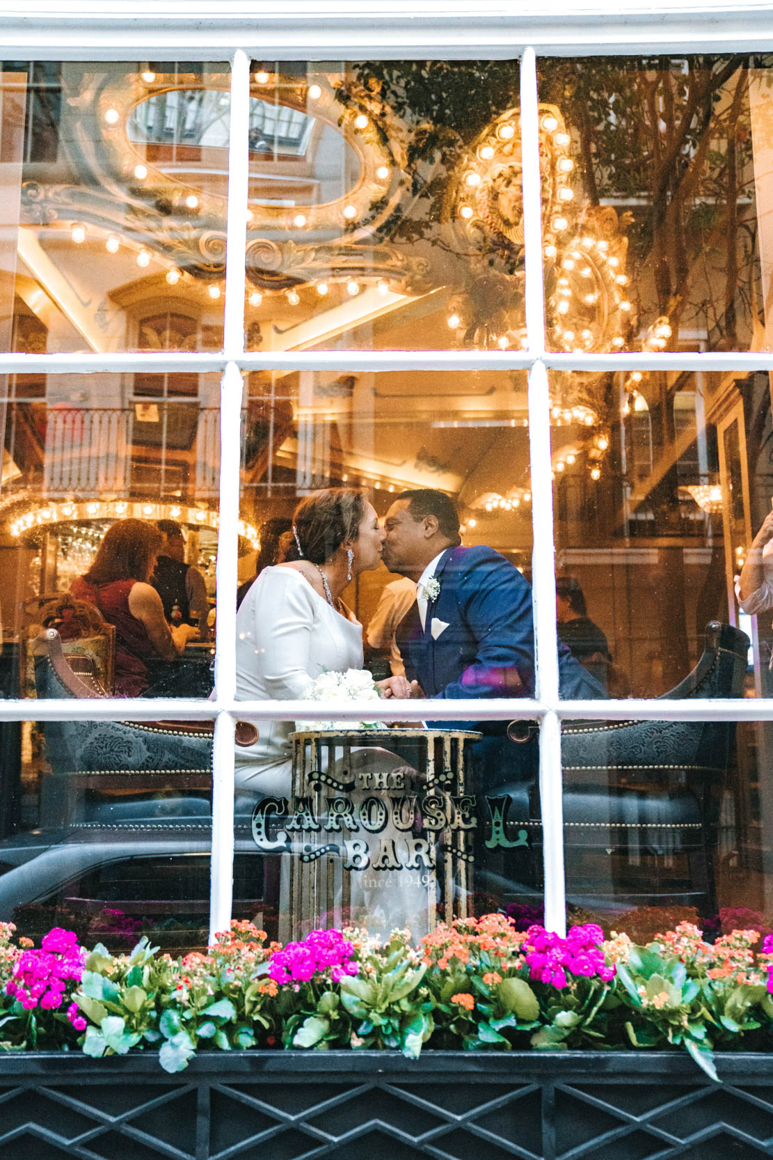 bride and groom kissing behind window at The Carousel Bar in the Hotel Monteleone in New Orleans