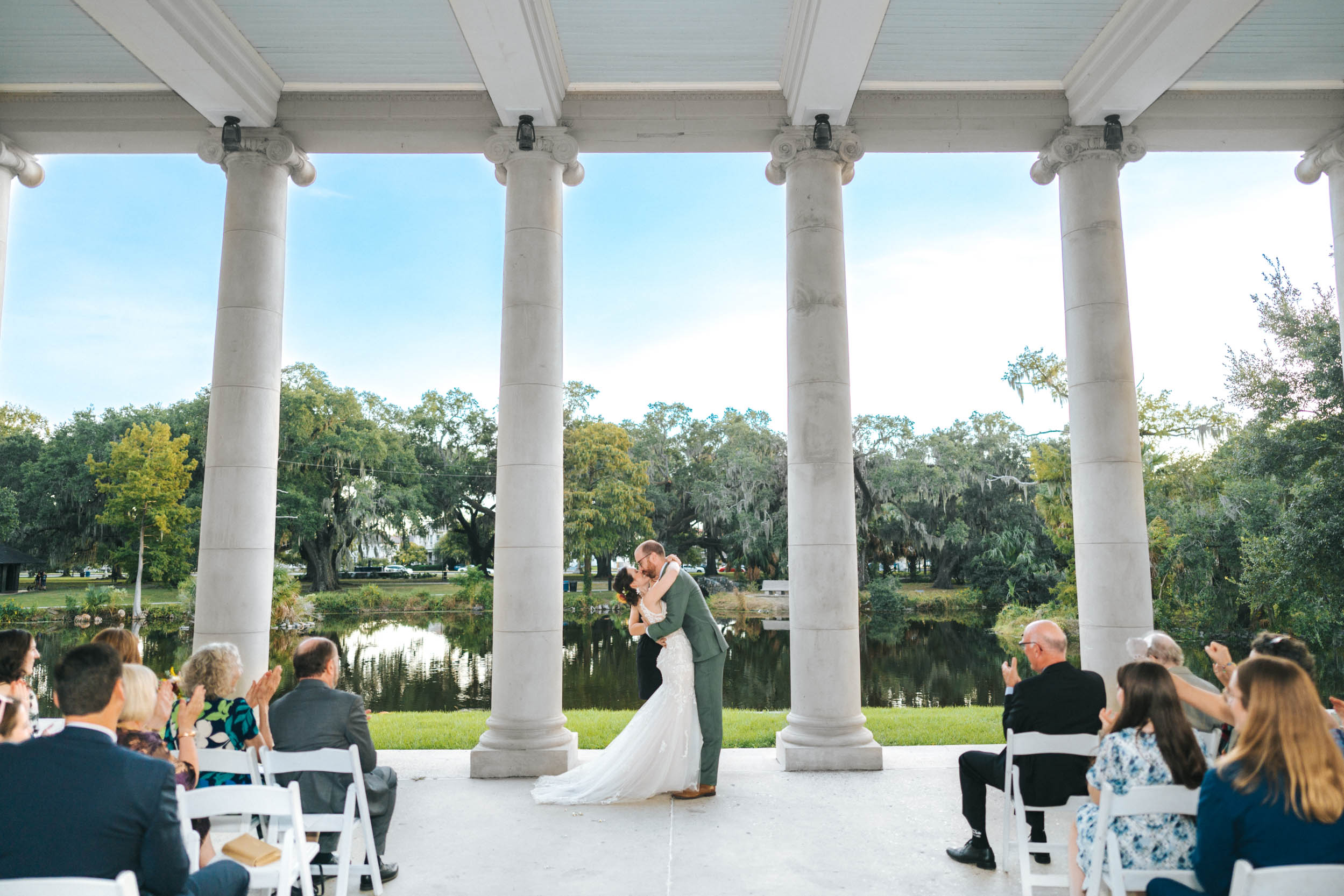 bride and groom kissing during wedding ceremony under peristyle in City Park New Orleans