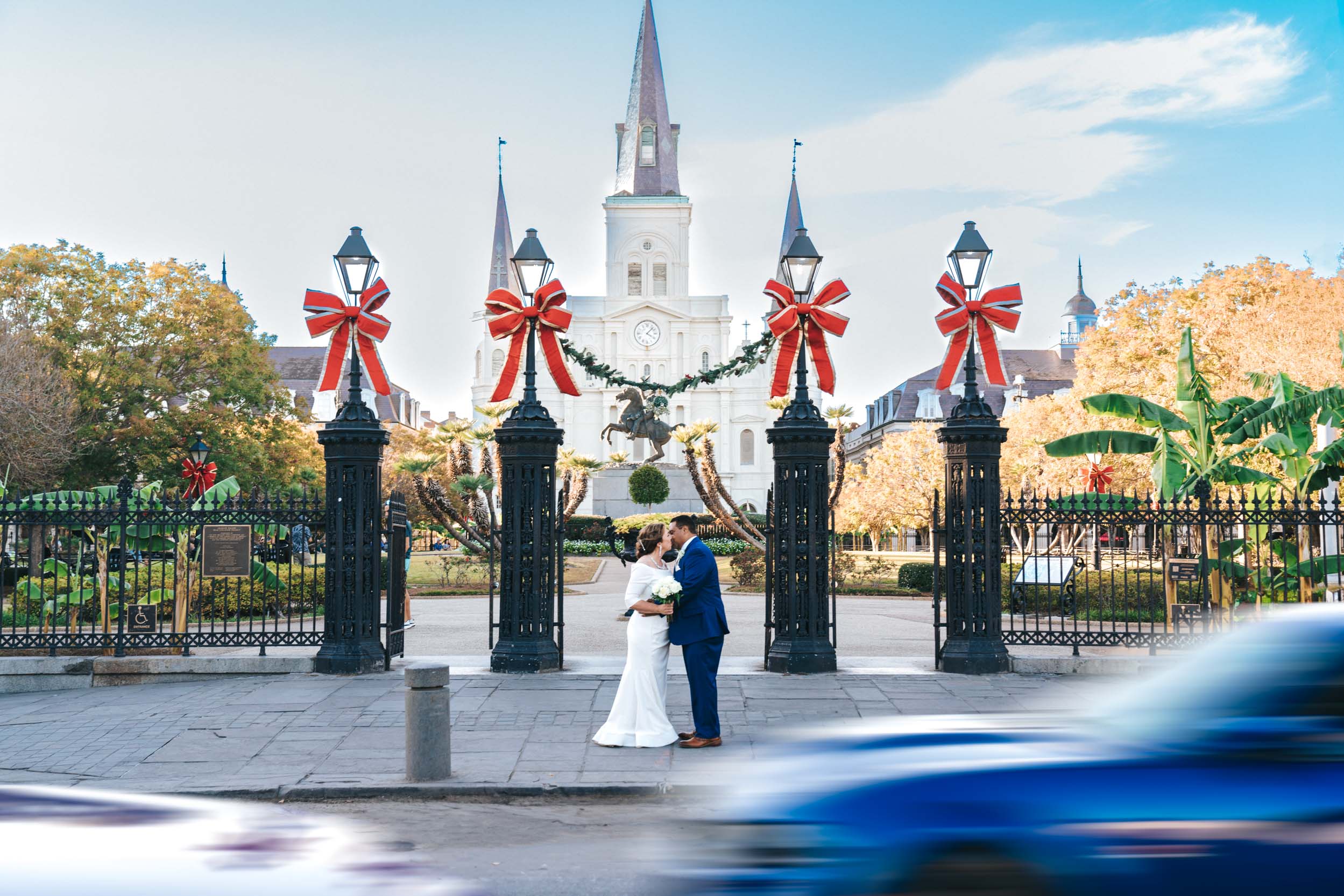 bride and groom kissing in front of Jackson Sqaure with cars passing by in New Orleans