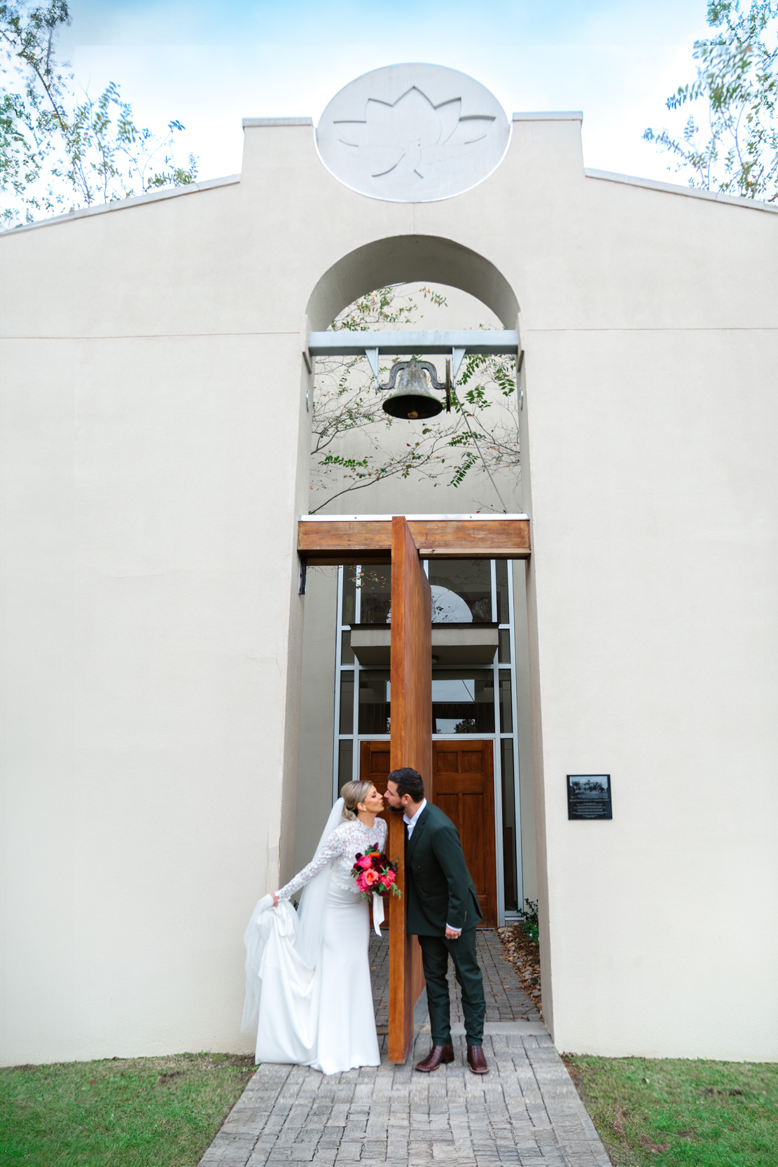 bride and groom kissing in front of St. Scholastica Academy church in Covington, Louisiana