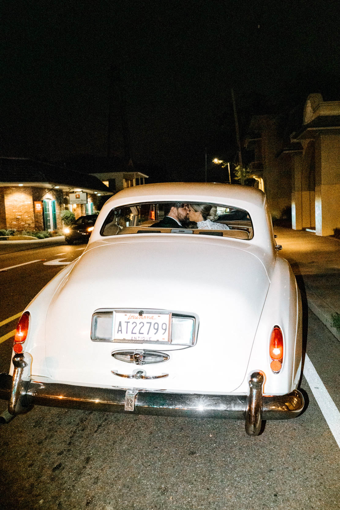 bride and groom kissing in the back of Rolls-Royce by Classic Motorcars (Daniel Moran) on wedding day on Boston Avenue in Covington, Louisiana