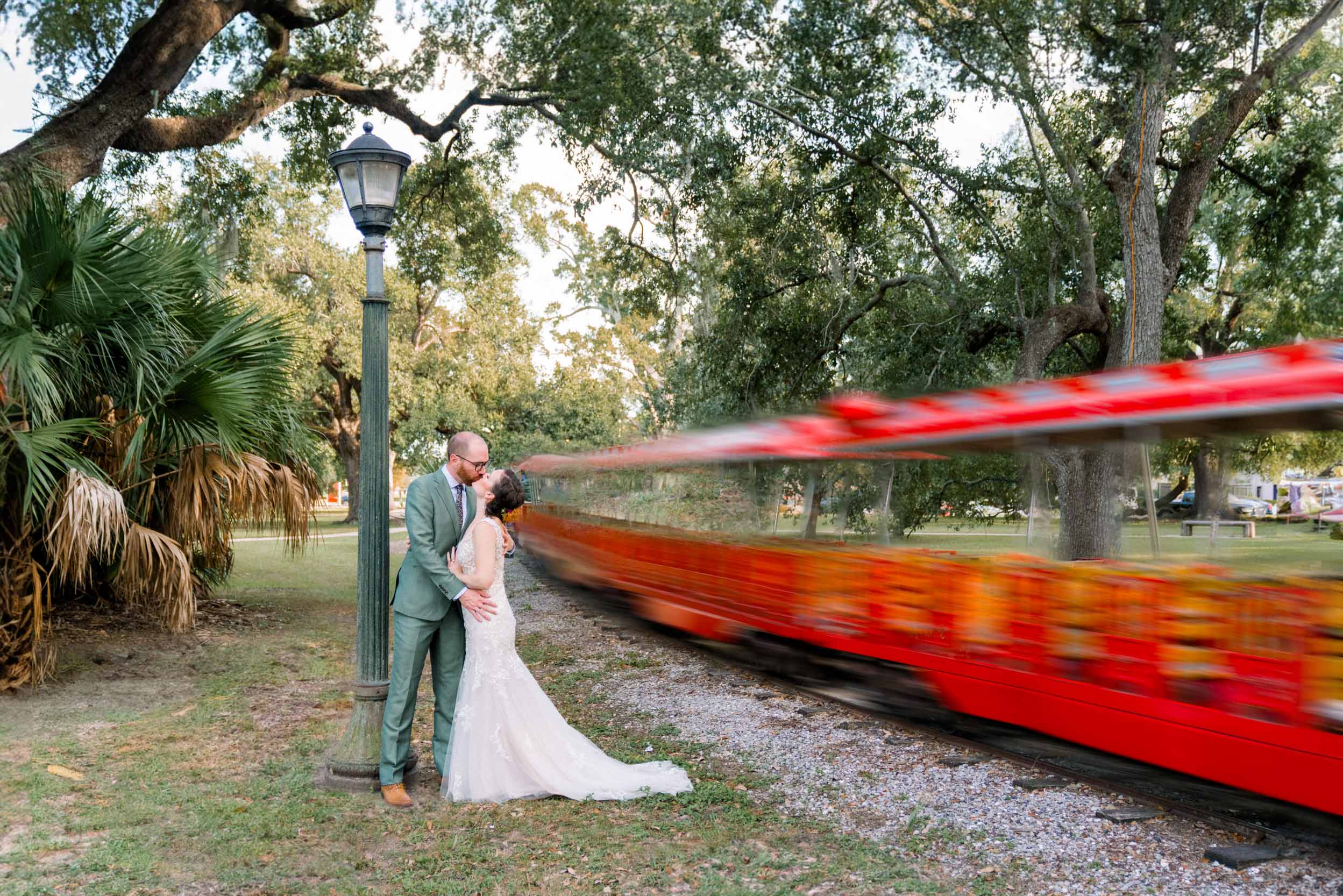 bride and groom kissing next to Story Land train at the Botanical Gardens in City Park New Orleans