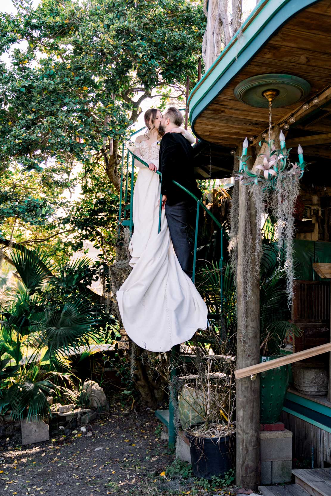 bride and groom kissing on spiral staircase in gardens of the Emerald Door in the New Orleans Bywater