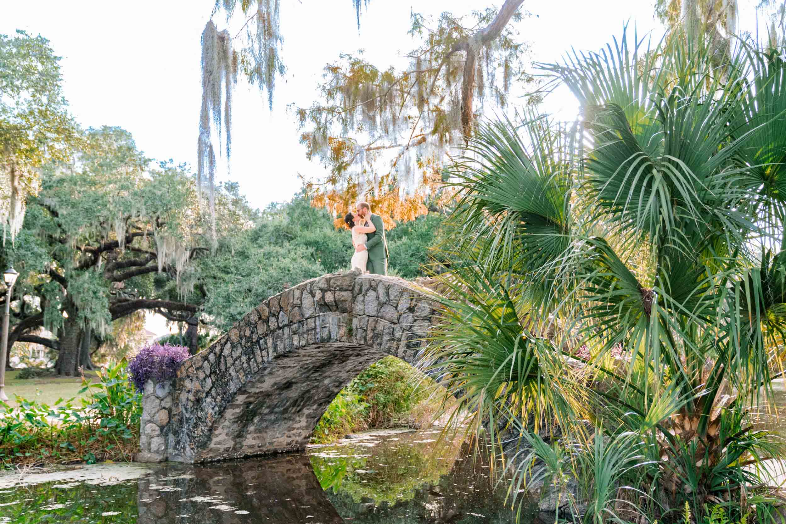 bride and groom kissing on stone bridge over bayou in New Orleans City Park