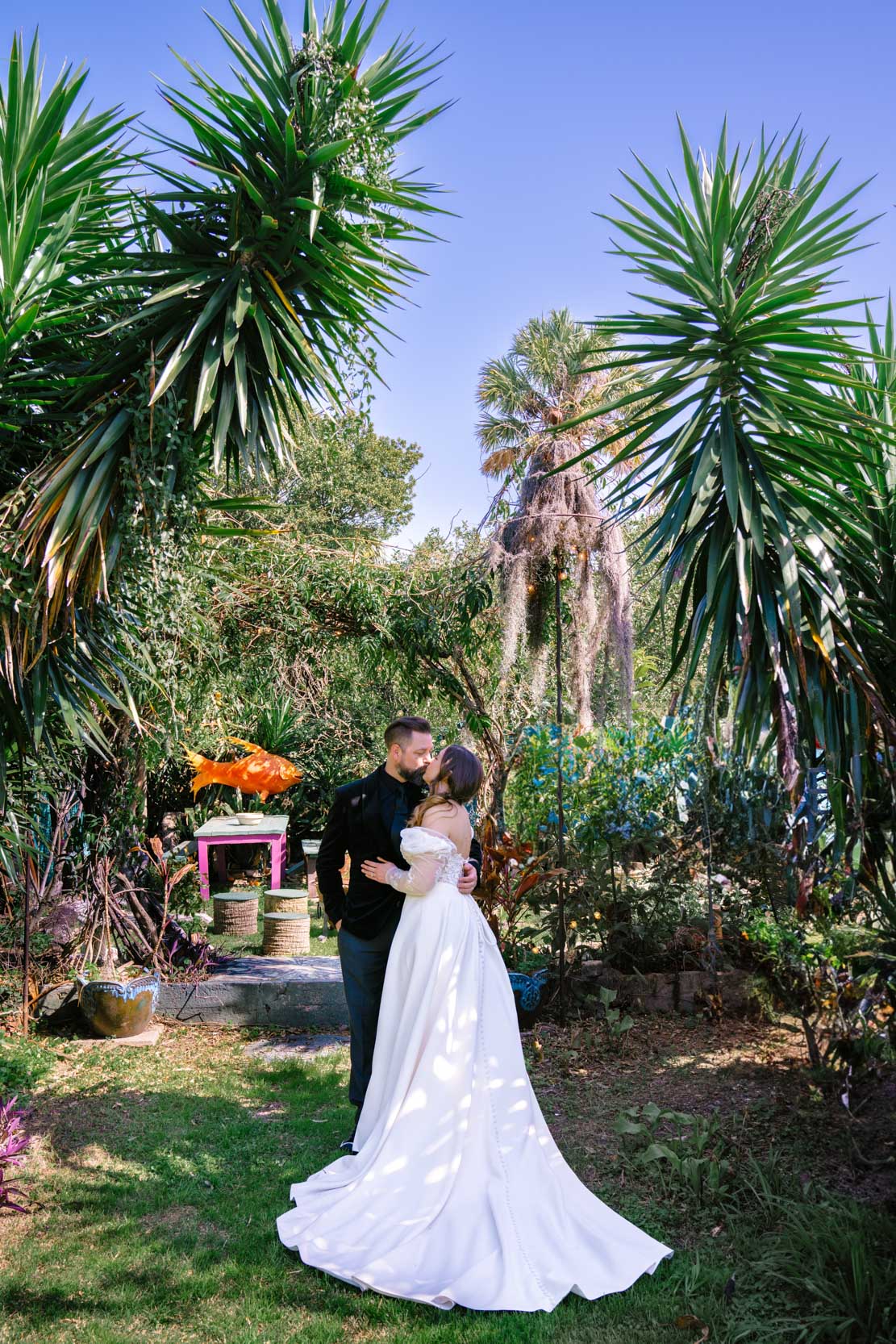 bride and groom kissing under tropical palm trees and garden at the Emerald Door in the New Orleans Bywater