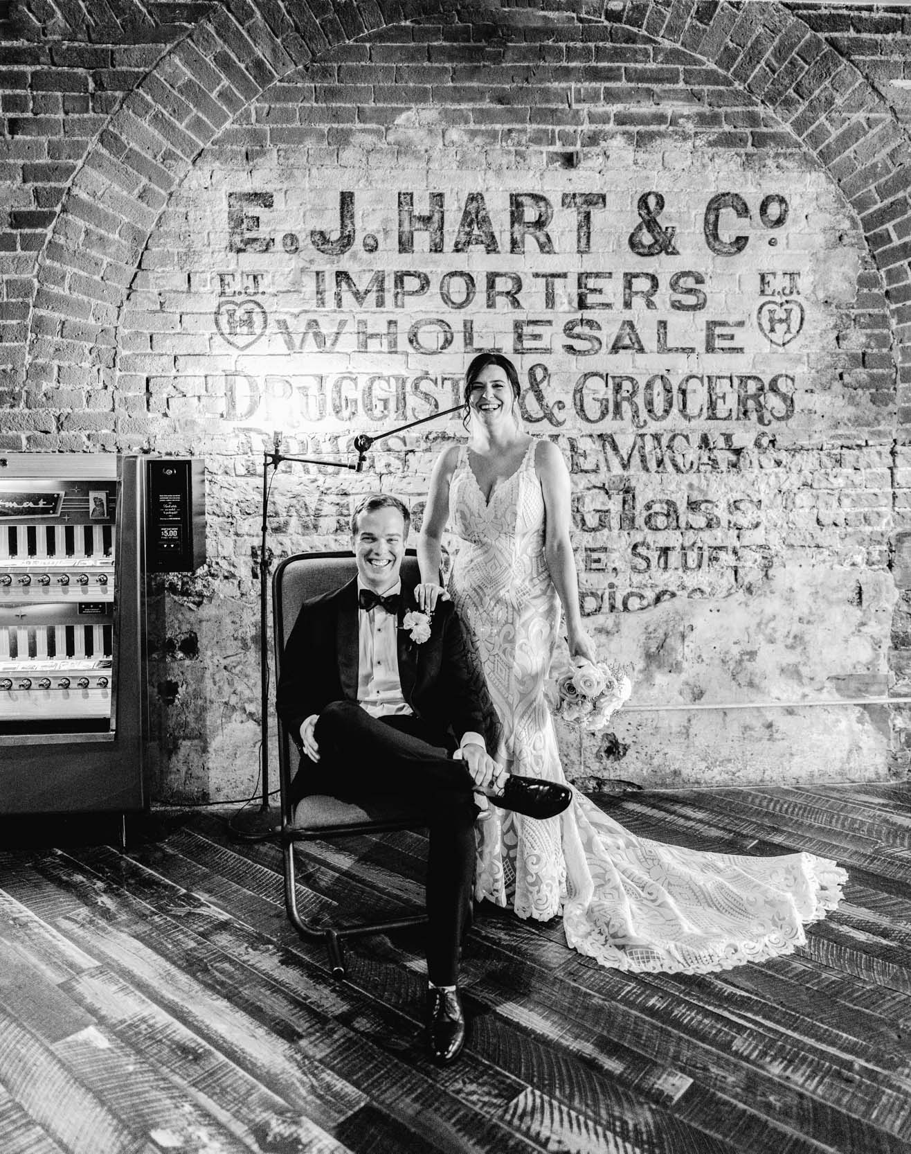 bride and groom laughing in front of rustic brick wall inside the Old 77 Hotel in New Orleans