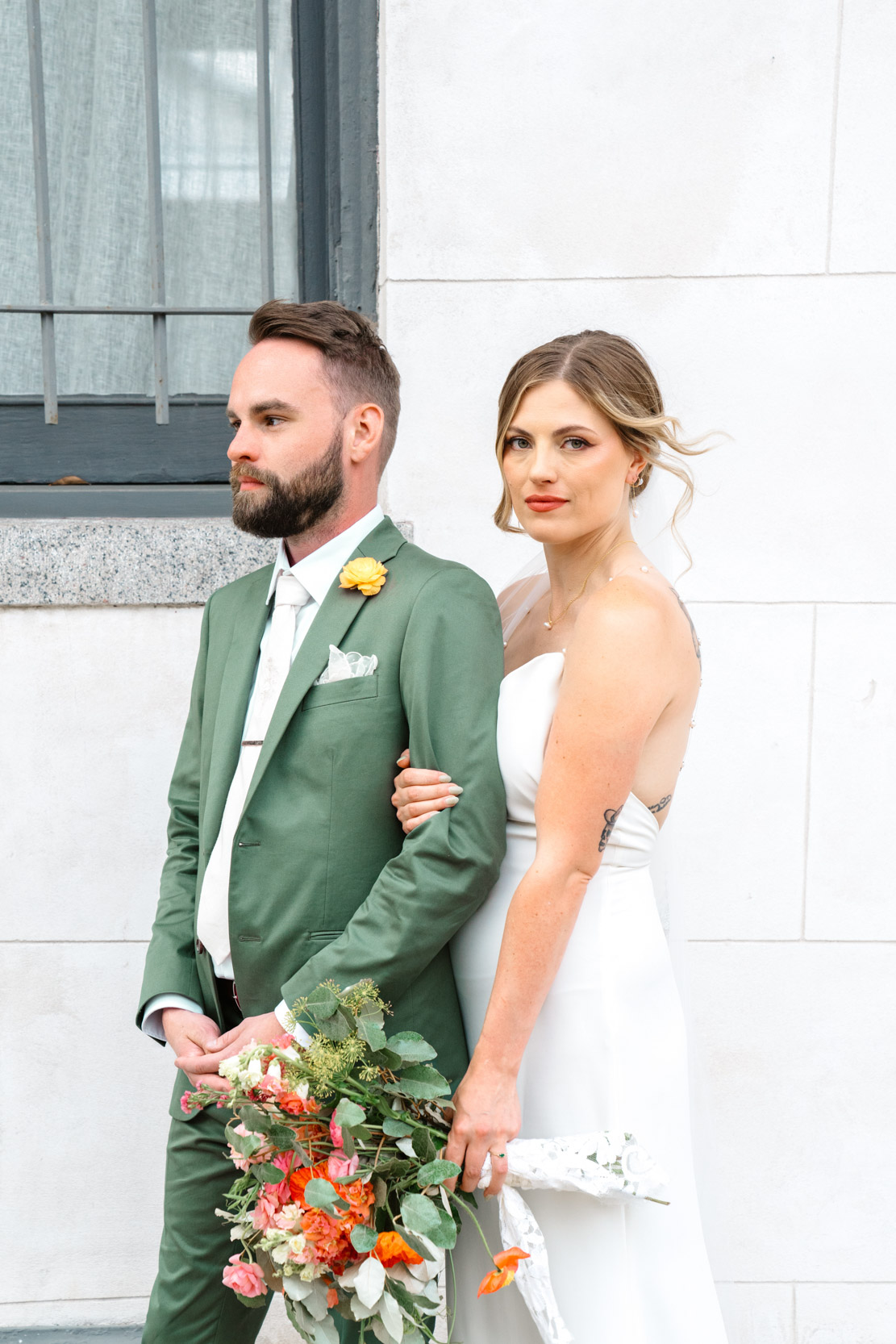 bride and groom posing and wrapping arms on wedding day with Cicada Calling flowers at Margaret Place in New Orleans