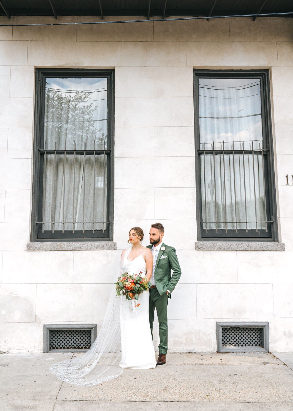 bride and groom posing in front of masonry mansion at Margaret Place in New Orleans