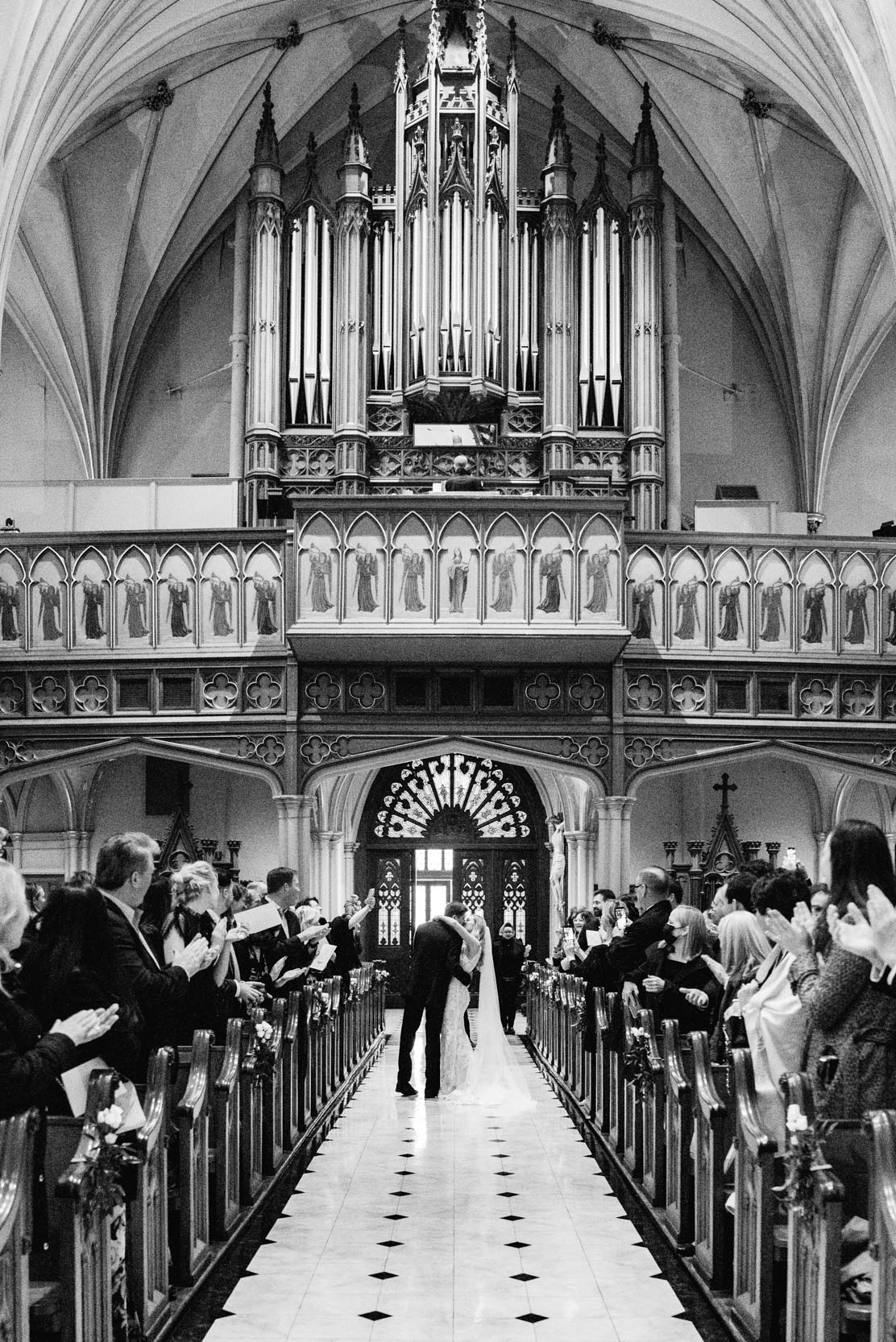 bride and groom stopping in the aisle to kiss while exiting wedding ceremony at St. Patrick’s Cathedral in New Orleans