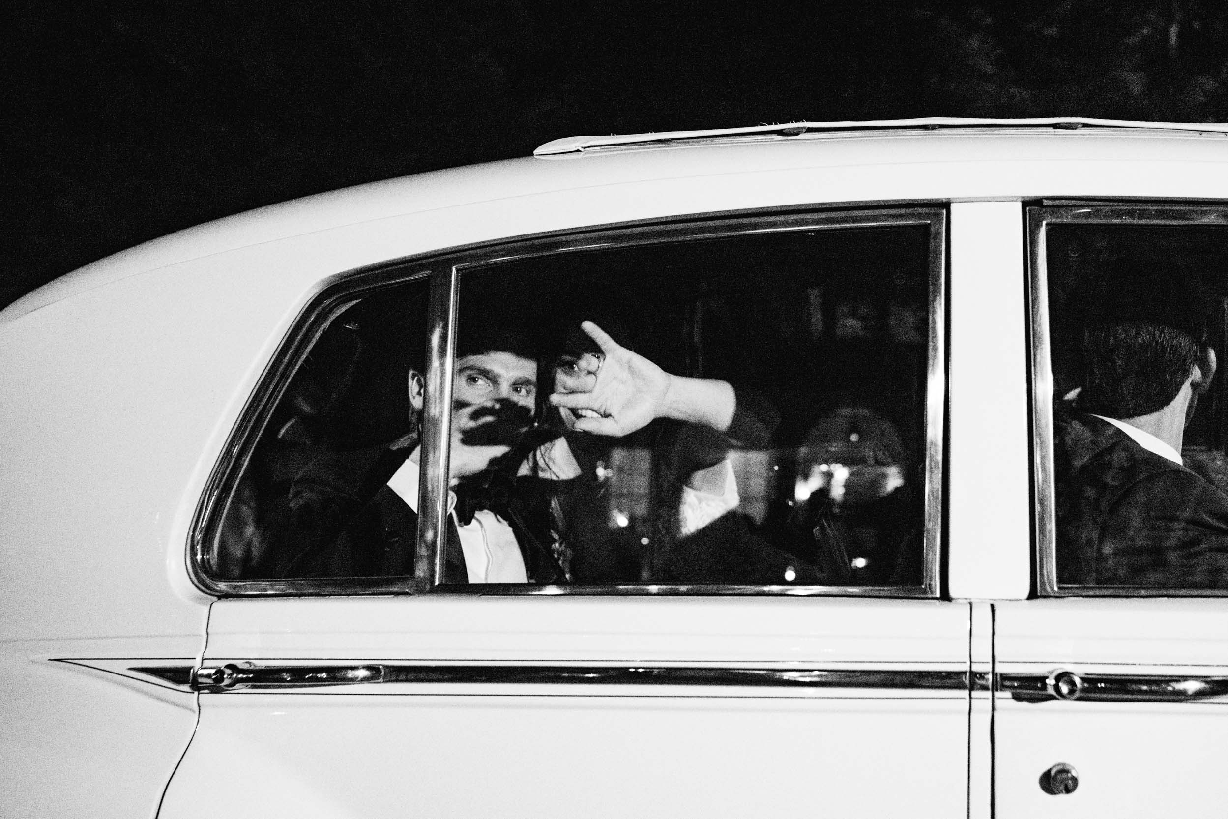 bride and groom waving inside getaway car and exiting on their wedding day in Covington, Louisiana