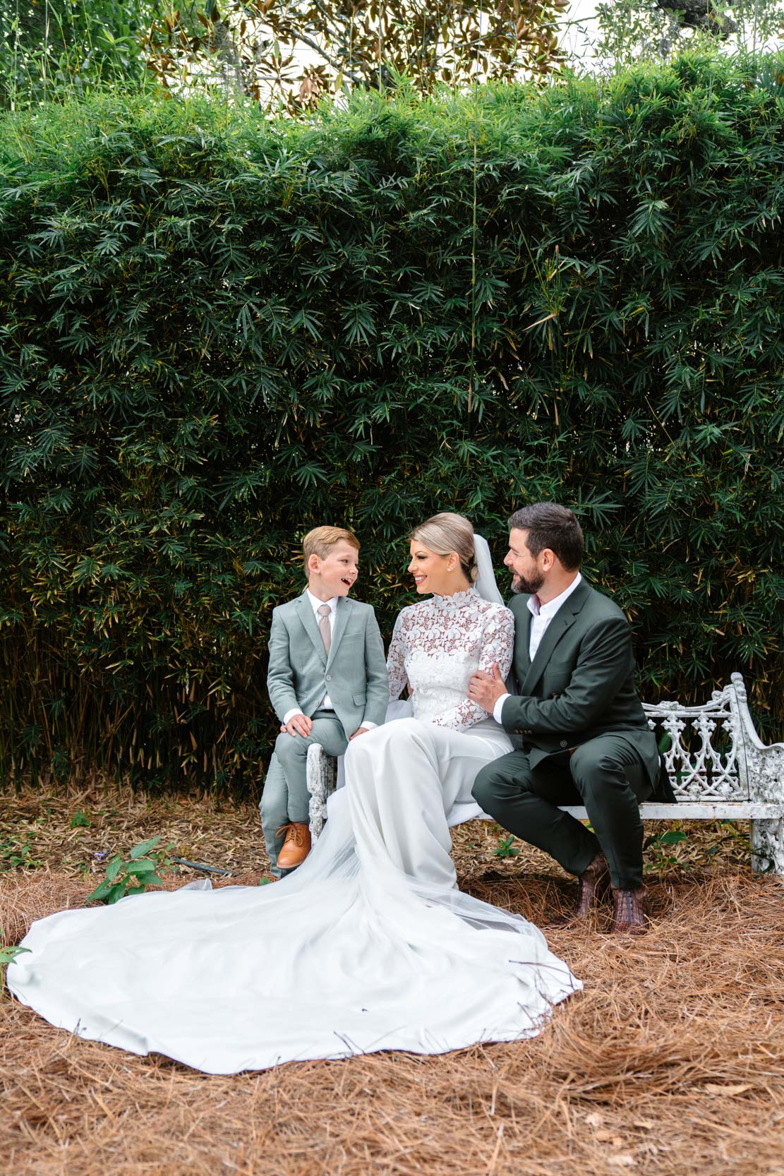 bride, groom, and their son sitting on wrought iron bench in garden at the Southern Hotel in Covington, Louisiana