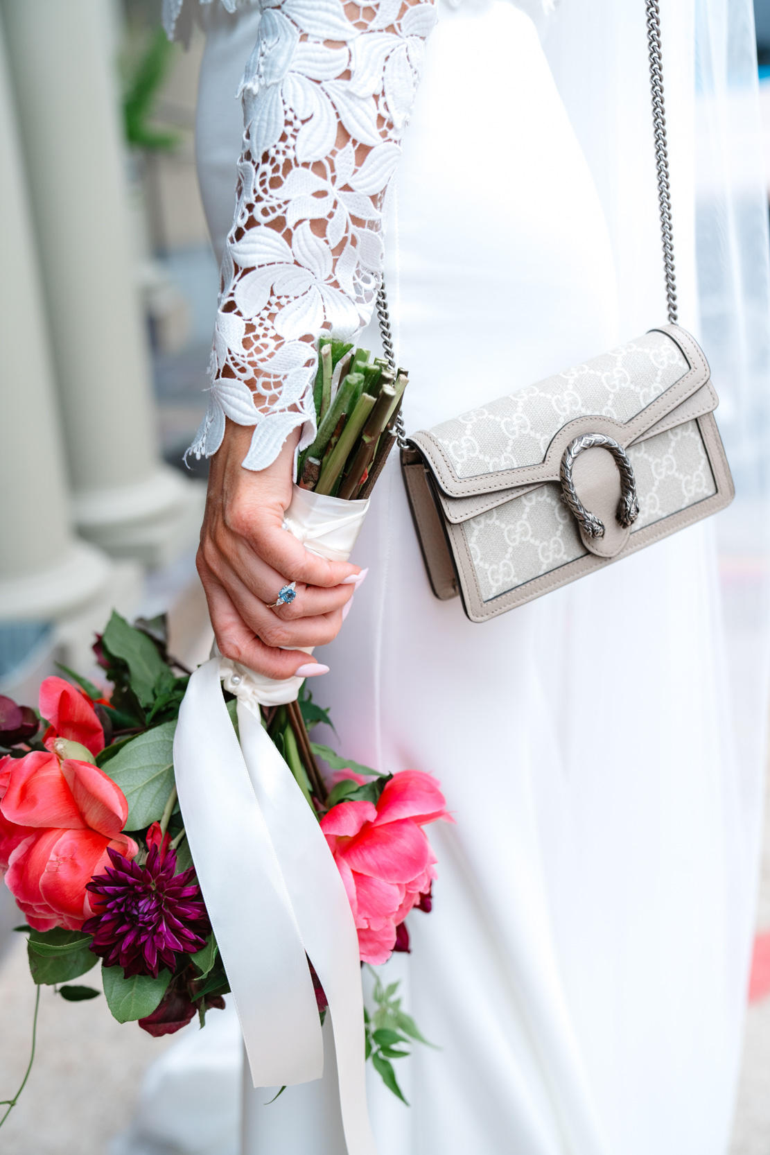 bride holding Petals and Parties flowers, Gucci purse, and wearing Chantilly laced top in front of the Southern Hotel in Covington, Louisiana