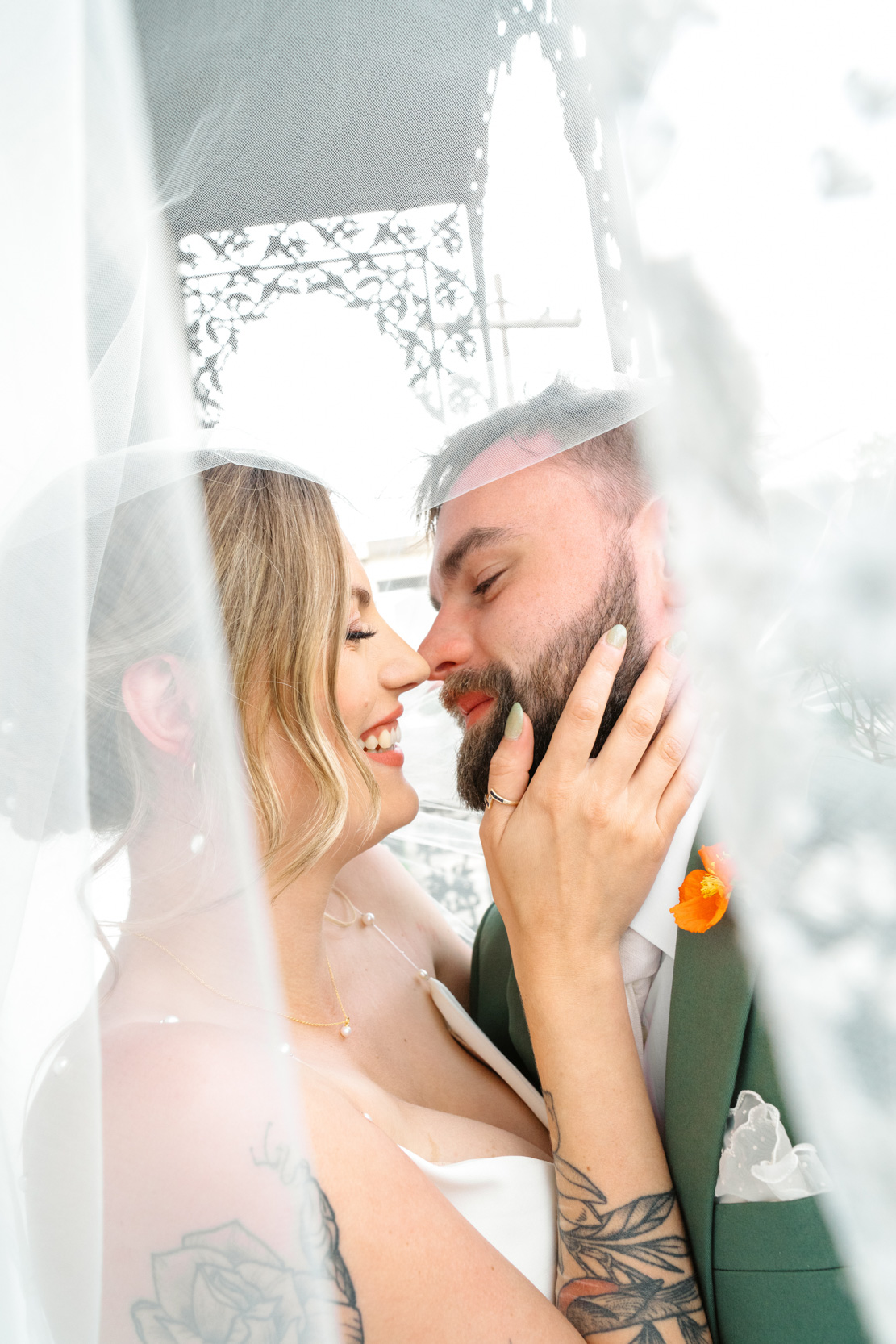 bride holding grooms face and smiling with veil over them at Margaret Place in New Orleans