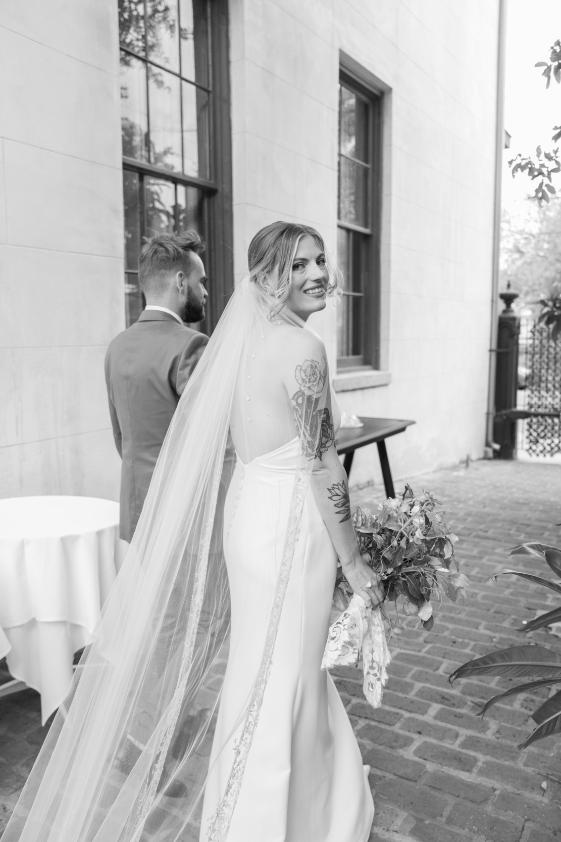 bride looking back while walking with groom at Margaret Place in New Orleans